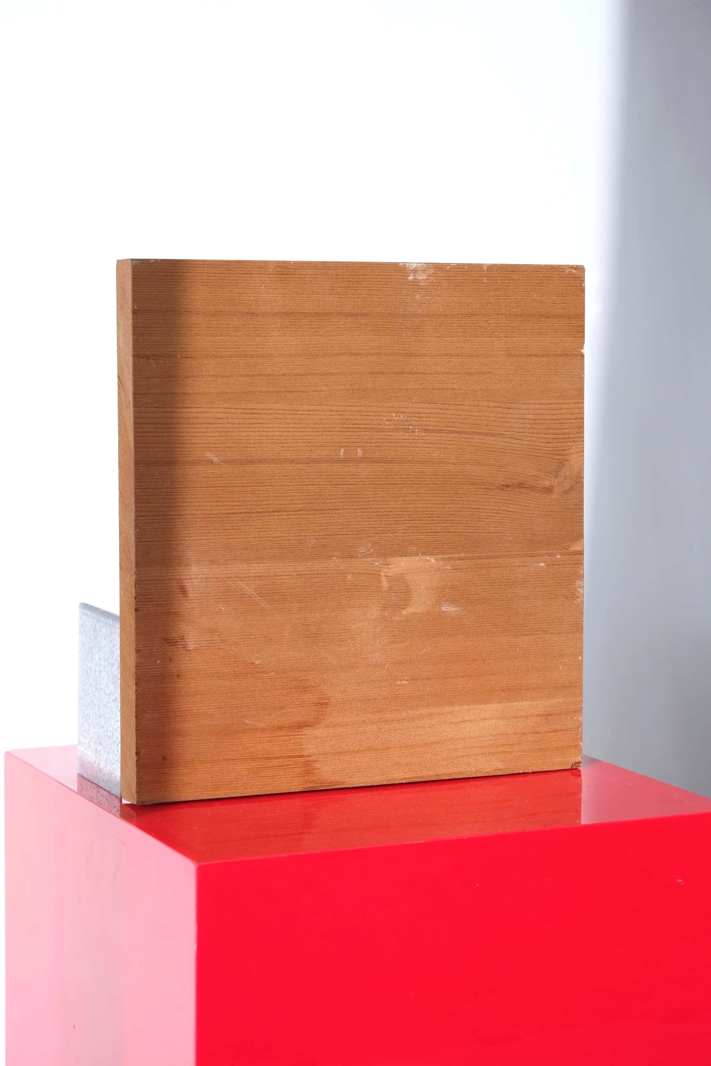 Back view of vintage Aigle boot display stand. Plain wooden backboard on a red pedestal.