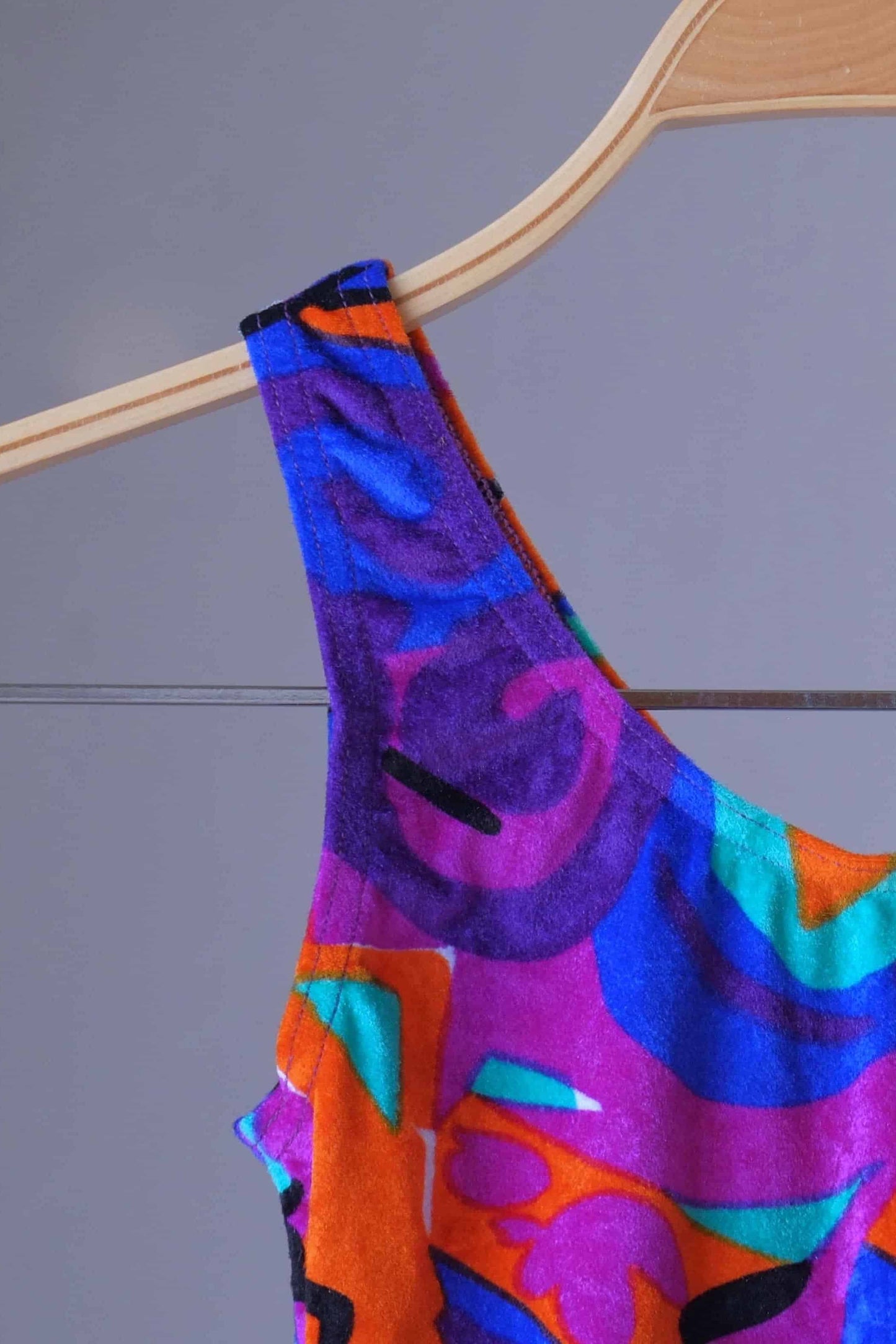 Close view of a colorful vintage Anniel one-piece leotard on a hanger.