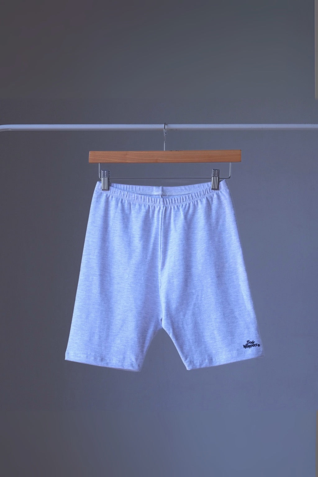 heather ash vintage 90s BODY WRAPPERS bike shorts on a hanger against a gray background.