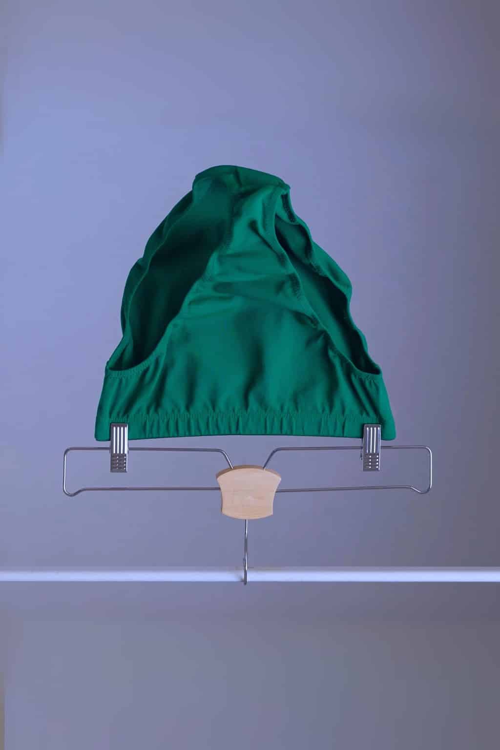 A pair of vintage Danskin high-cut dance briefs in emerald green, hanging on a clothes rack.