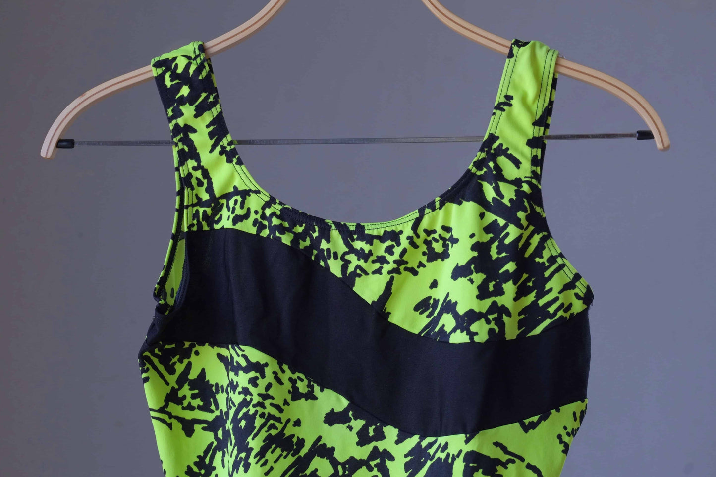 Close-up of the vintage Danskin leotard's neon green abstract print and black panel.