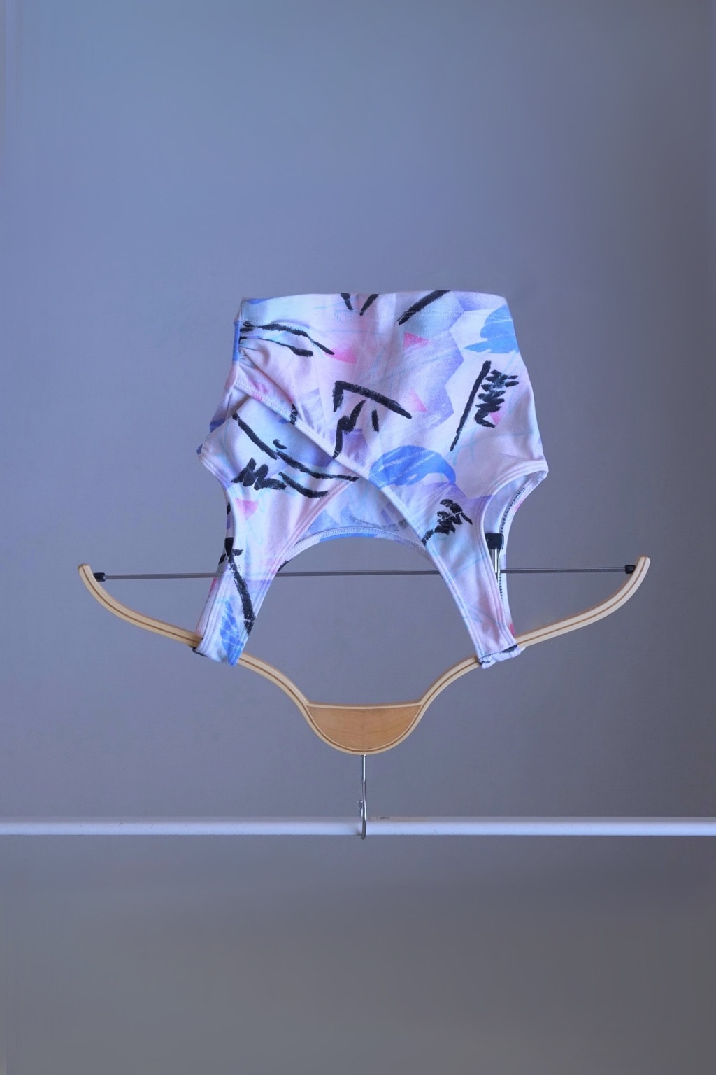 A DANSKIN vintage 90s abstract pastel print crop top, displayed on a hanger.
