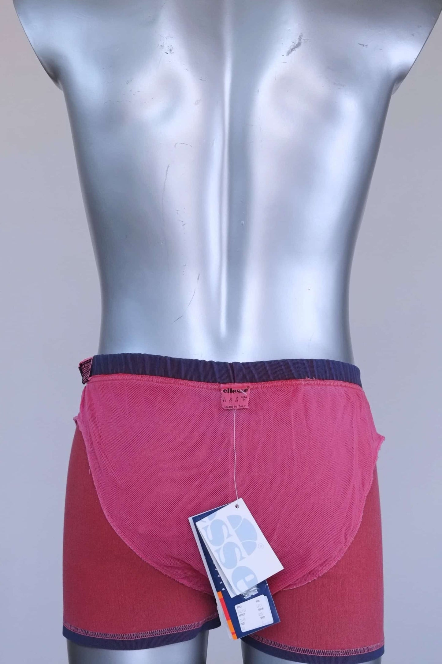 Interior view of vintage Ellesse swim trunks showing pink mesh lining and size tag.