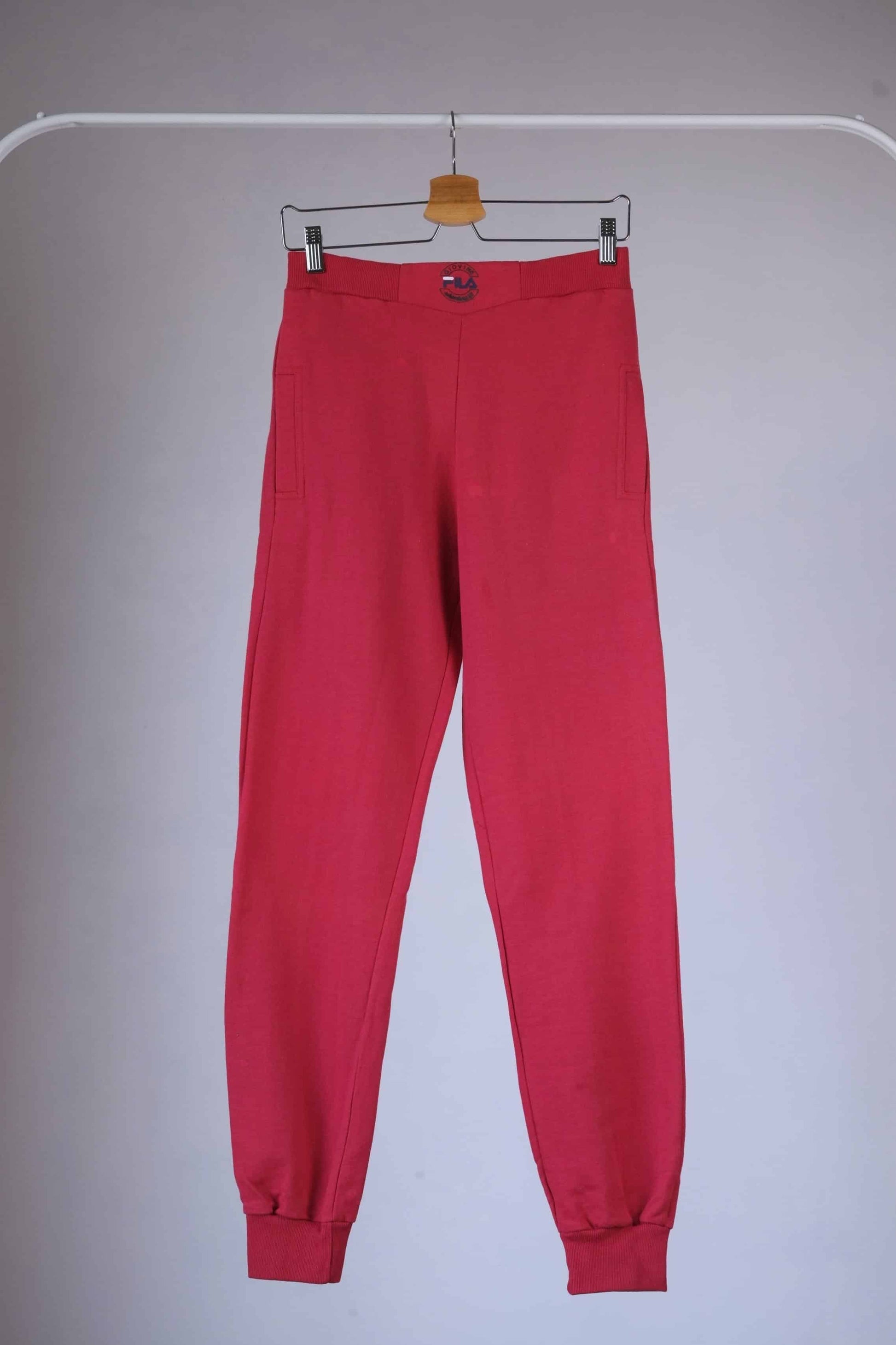 Red Fila 90s vintage jogging pants hanging on a hanger.