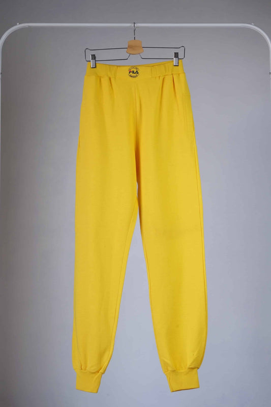 Yellow Fila 90s vintage jogging pants hanging on a hanger.