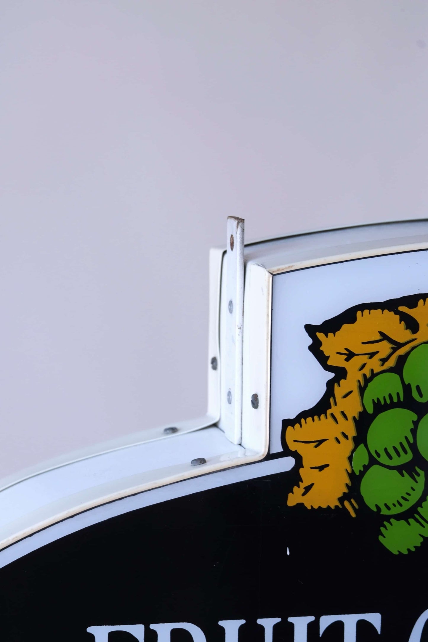 Close-up of upper mounting corner and fruit logo on 1990s Fruit of the Loom neon-style sign.