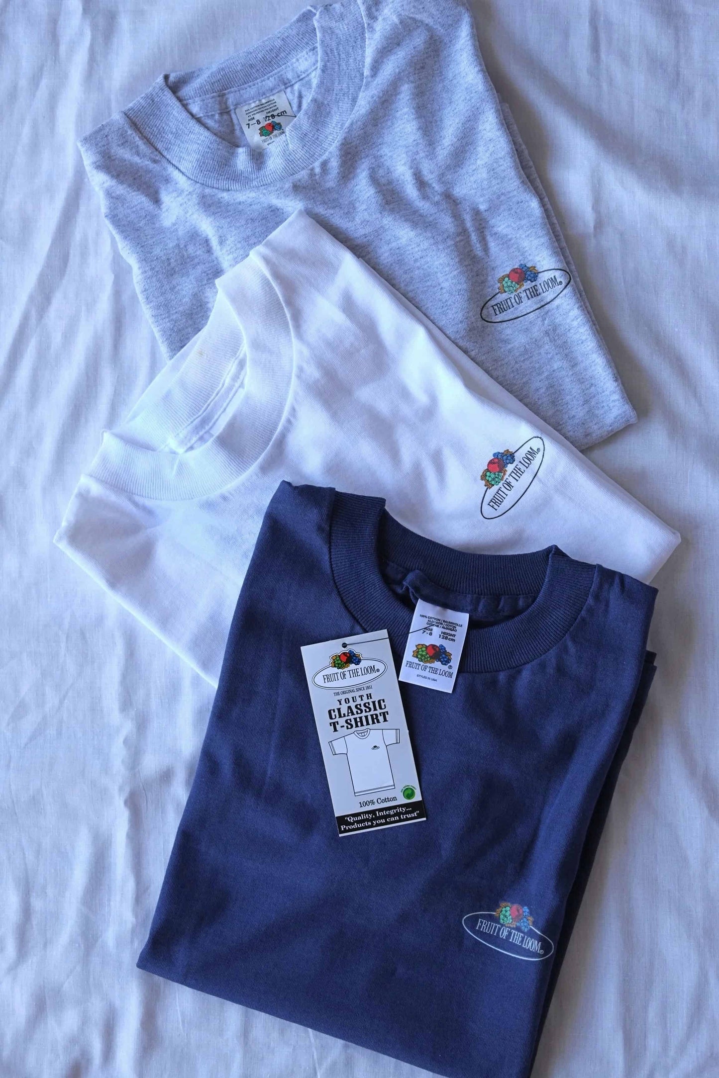 3 folded FRUIT OF THE LOOM Kids Classic T-shirts in ash gray, in white and in navy