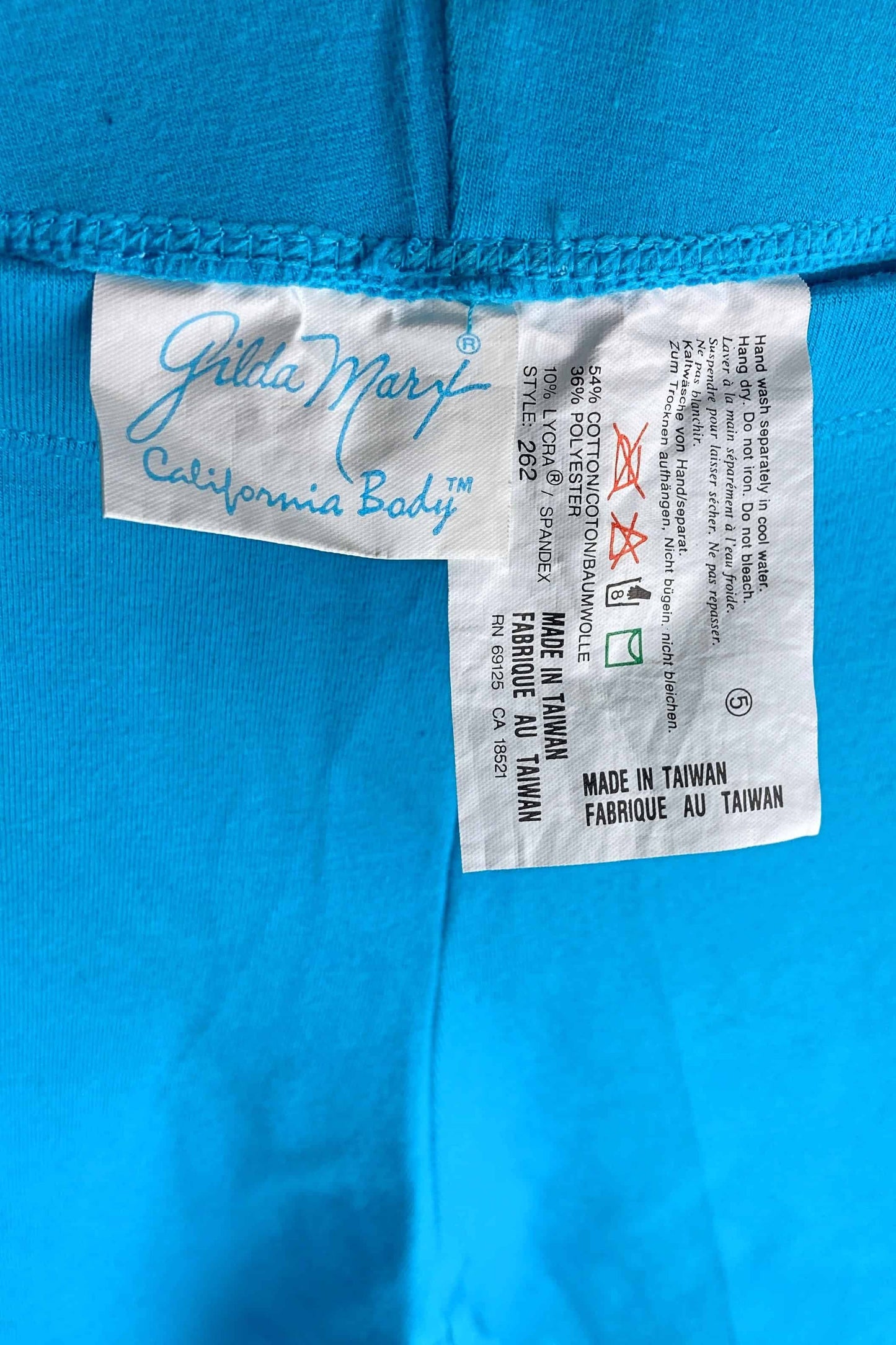 A close-up of the brand and care tag on a pair of blue vintage GILDA MARX leggings, showing the logo and fabric content.