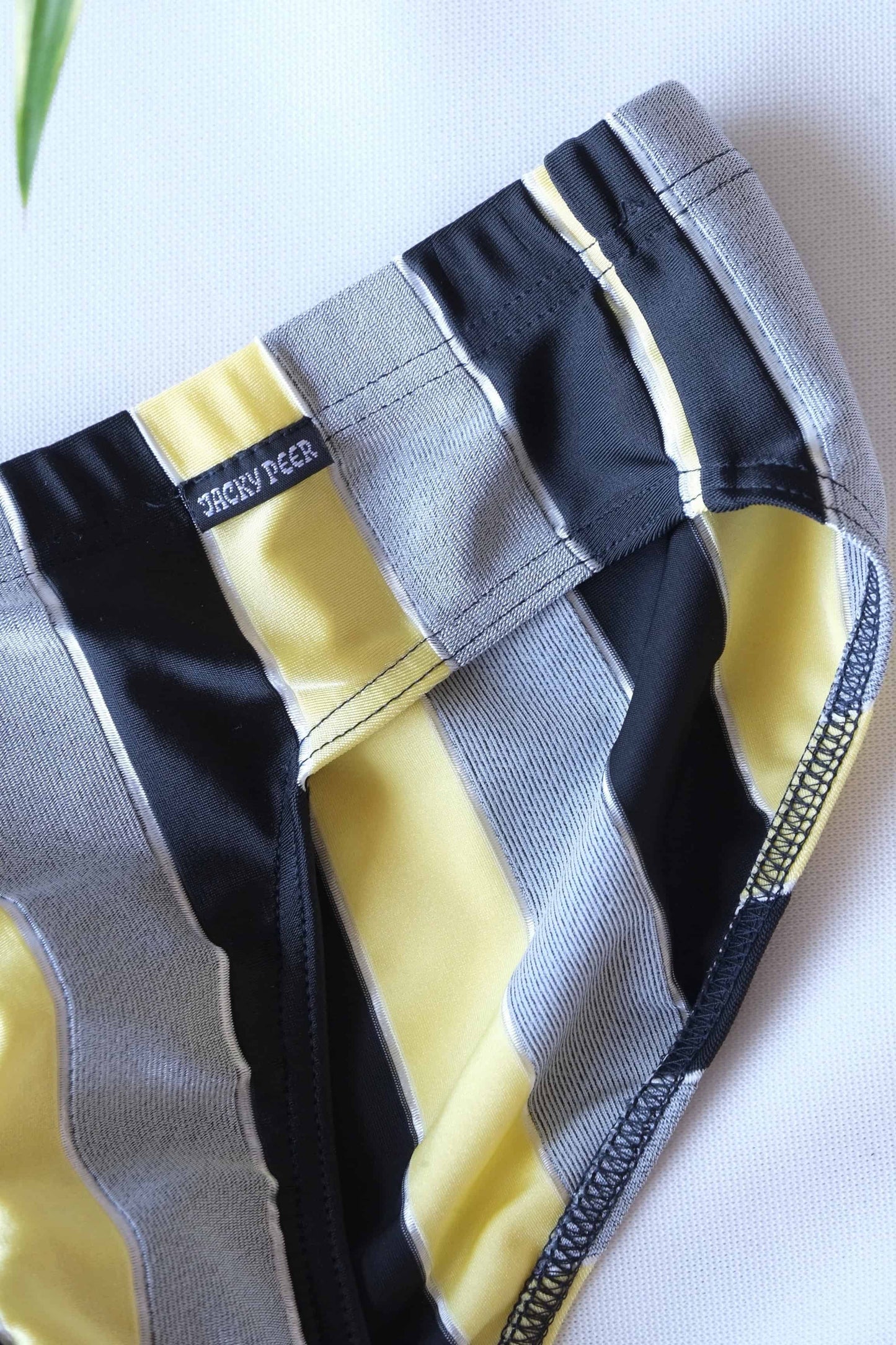 Close shot of a pair of JACKY PEER Vintage black, grey and yellow Striped Swim Briefs.