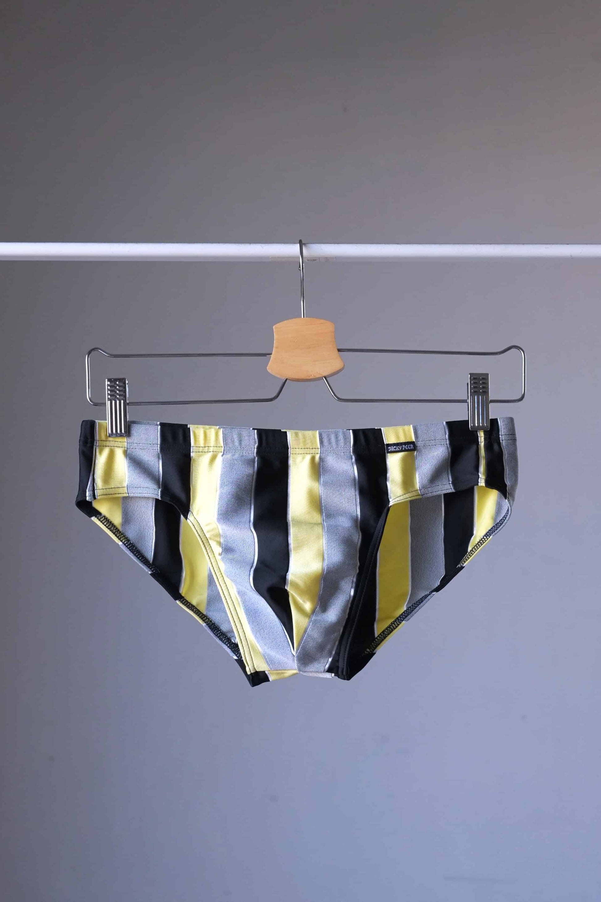 JACKY PEER Vintage black, grey and yellow Striped Swim Briefs displayed on hanger.
