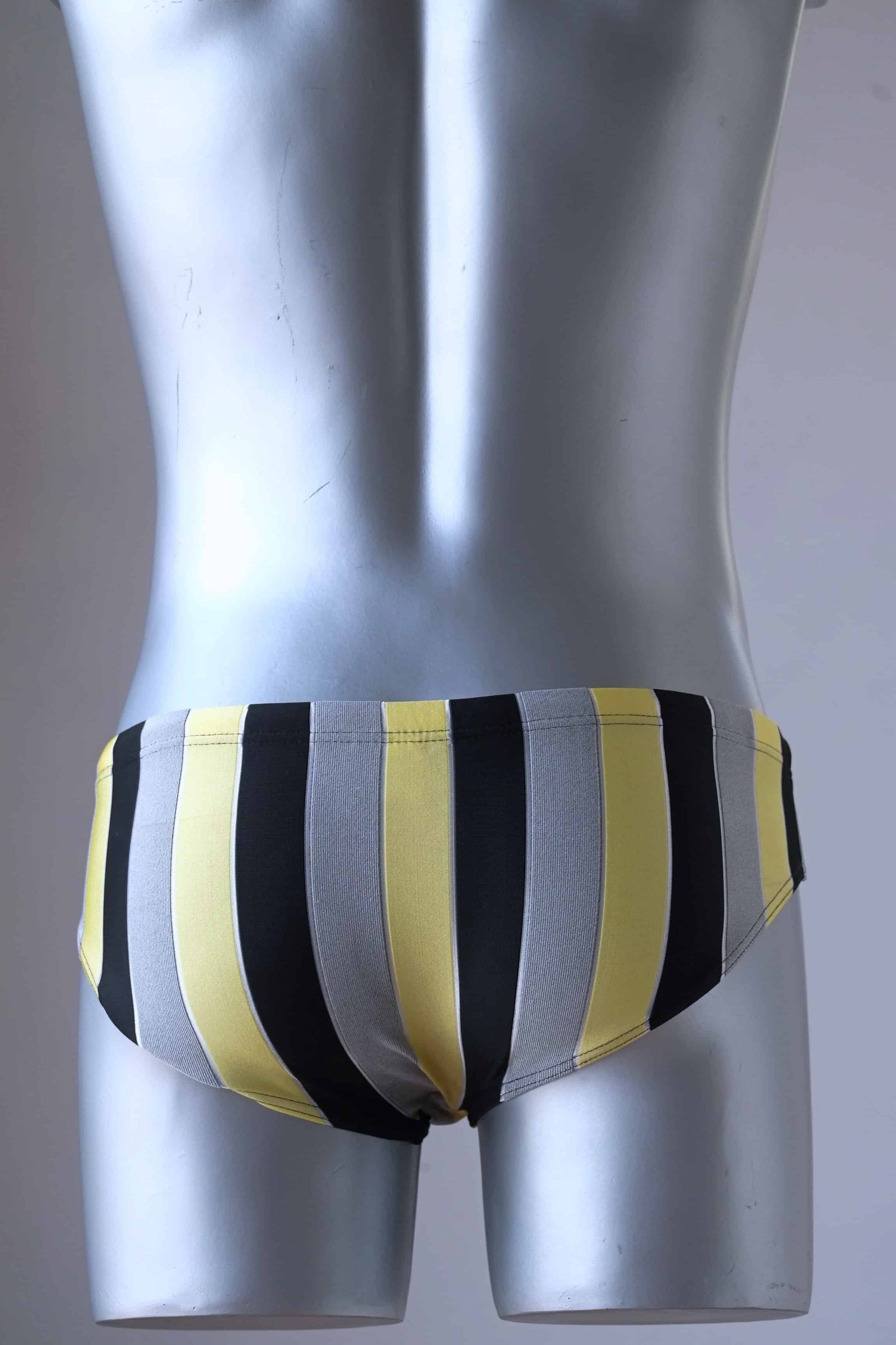 JACKY PEER Vintage black, grey and yellow Striped Swim Briefs worn by mannequin, photographed from behind.