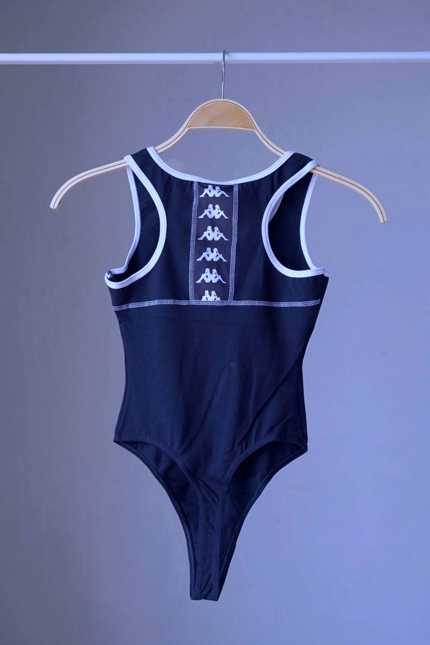 Back view of a navy KAPPA vintage 90s women's activewear leotard with white trim and a chest logo, displayed on a wooden hanger.