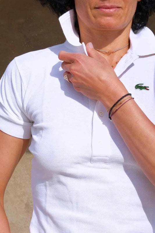 Close shot of Model wearing a white Lacoste polo shirt over denim cut off shorts, standing outside in a sunny spot.