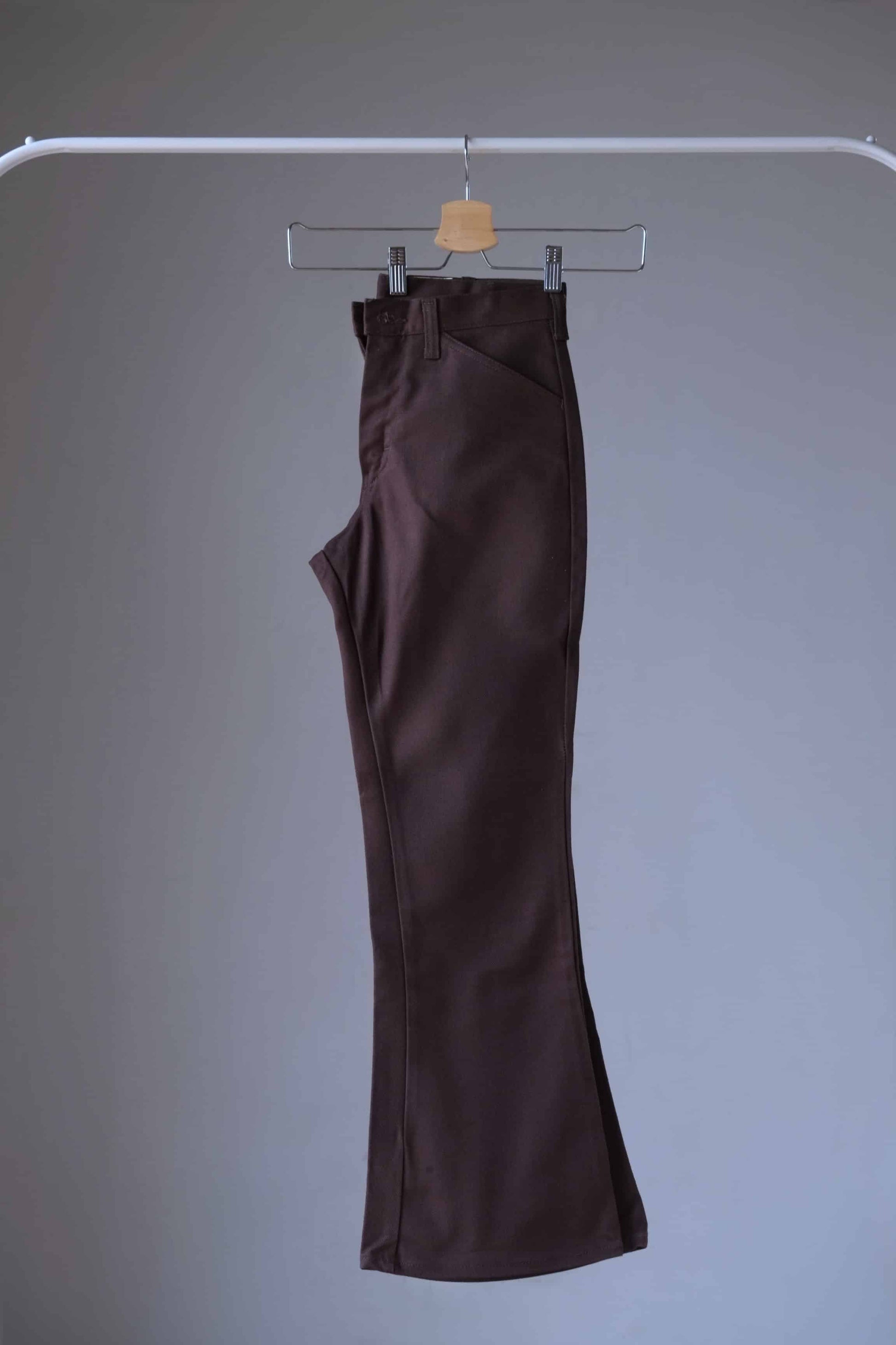 Side view of a pair of brown Vintage Lee flared pants on hanger