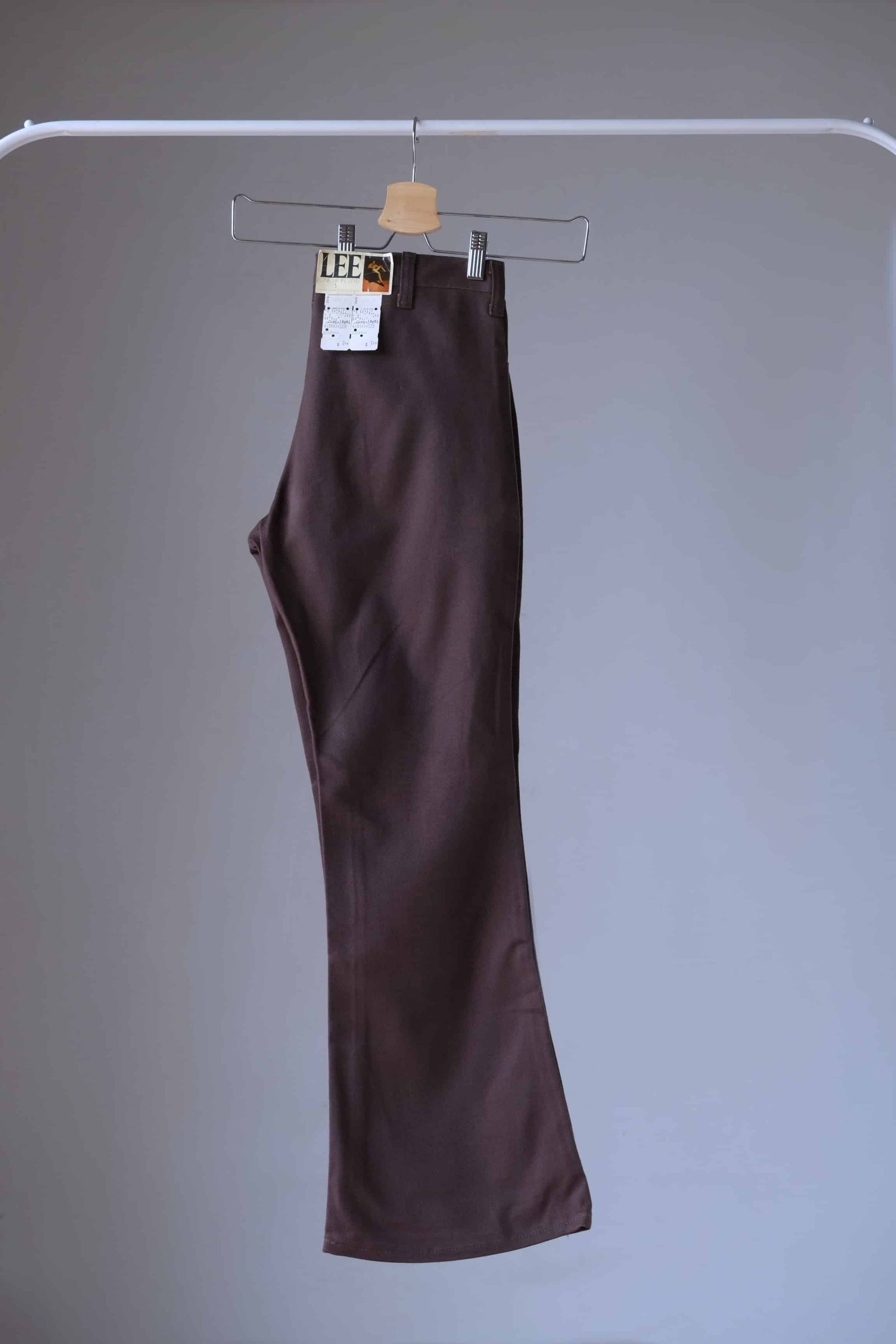 Side view of a pair of brown Vintage Lee flared pants on hanger showing the tag