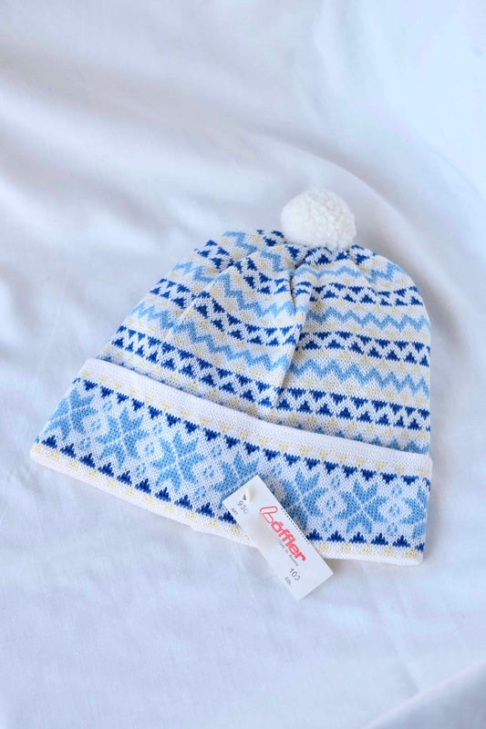 LÖFFLER 90's Vintage Ski Beanie in white and light blue snowflake design with the tag showing