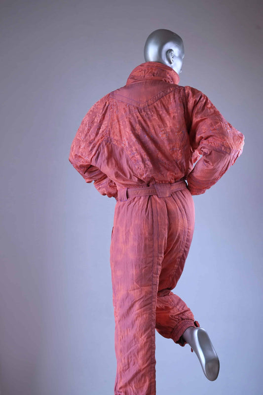 A back view of a coral vintage 90s ski suit, shown on a mannequin with one leg raised.