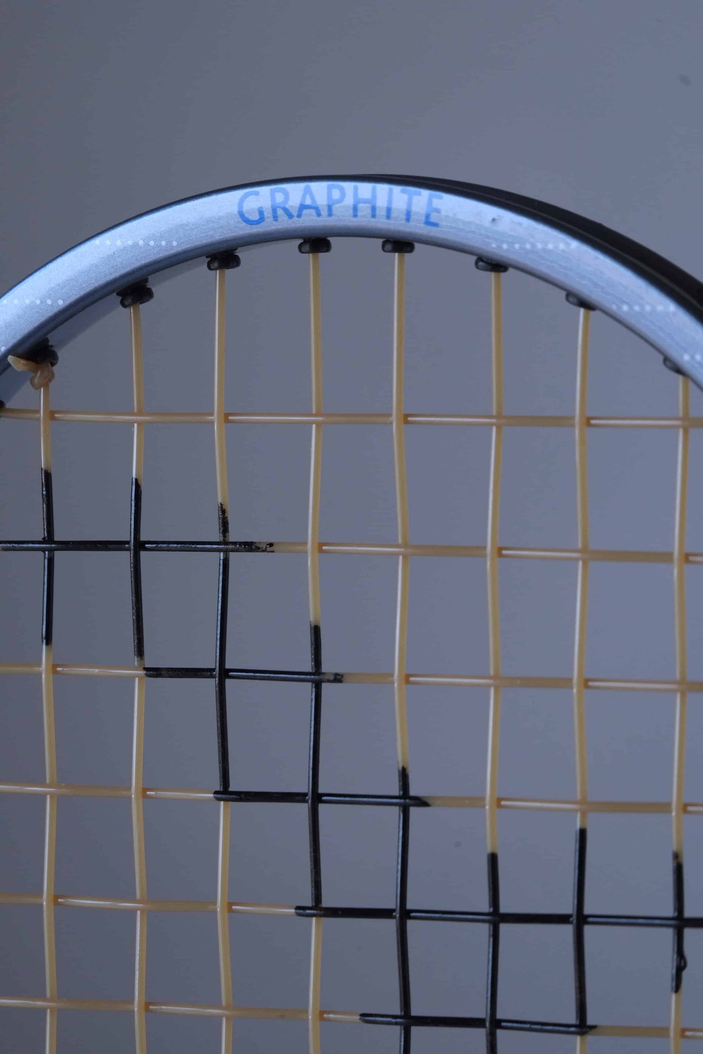 Close-up of a vintage Snauwaert Hi-Ten 25. The word "GRAPHITE" is written in blue along the top edge of the frame. The strings are yellow with part of the black painted logo showing.