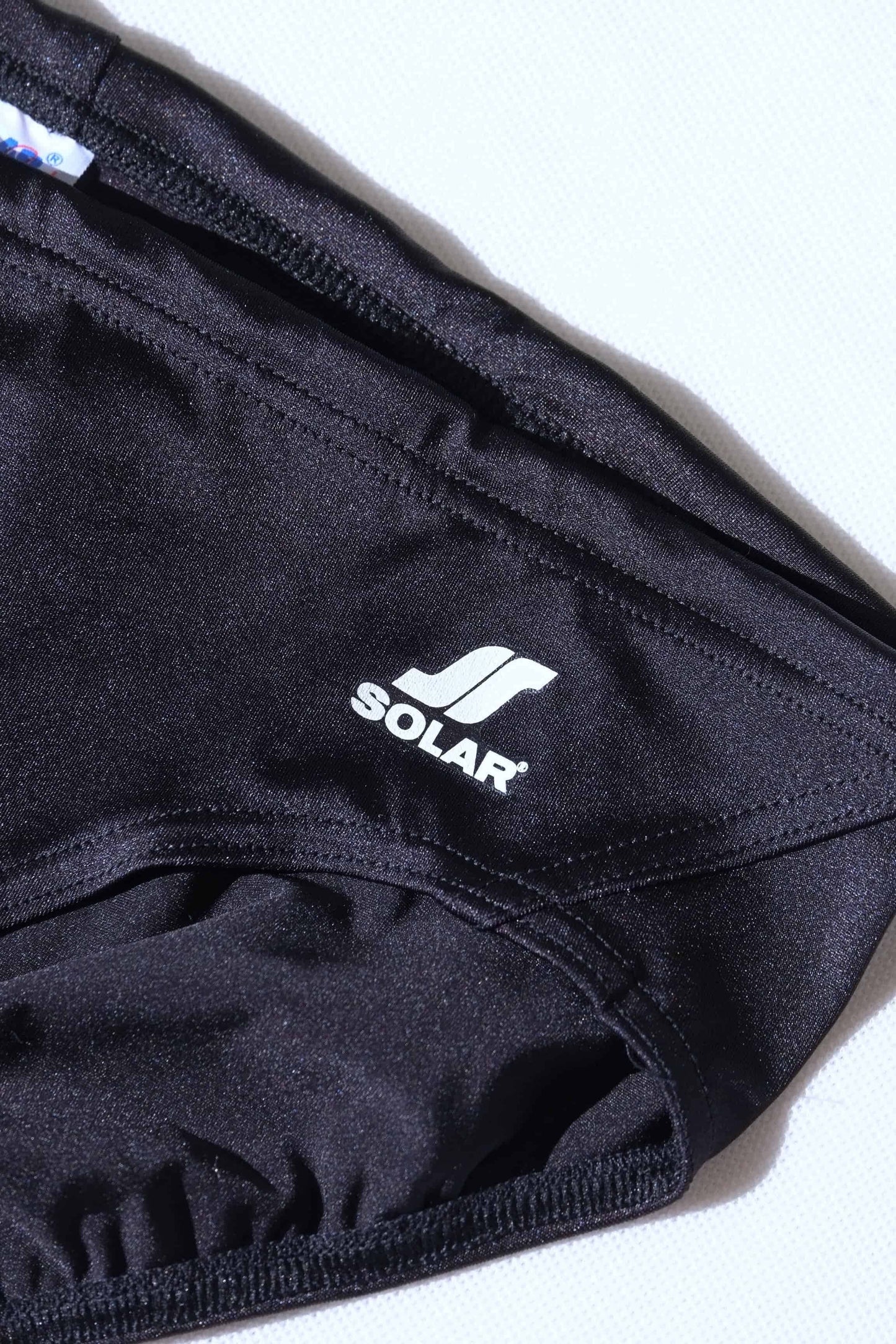 Close up of vintage Black swim briefs with Solar logo on a white background