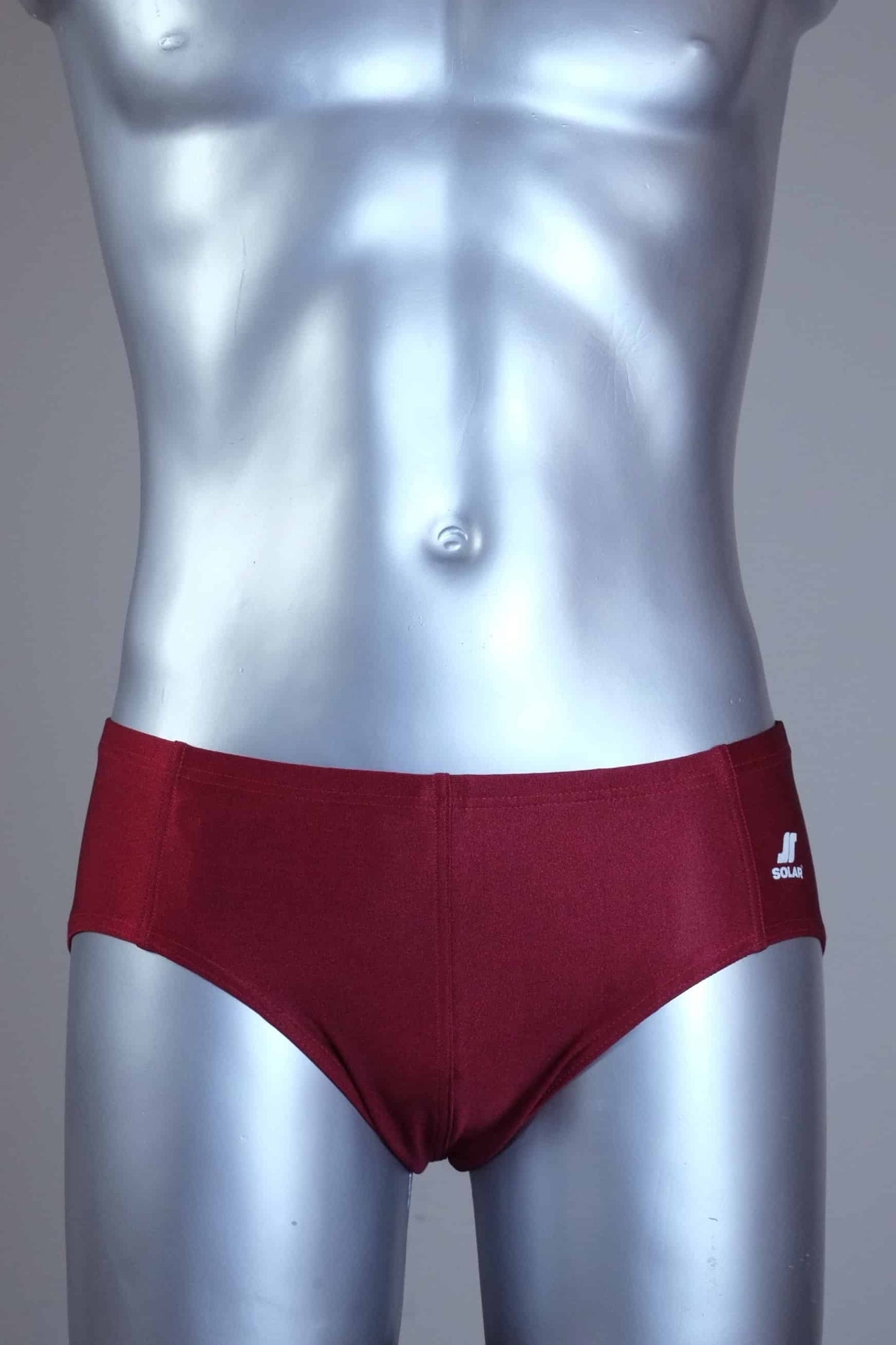 Mannequin wearing a pair of vintage 70s burgundy swim briefs with a visible brand logo on a gray background