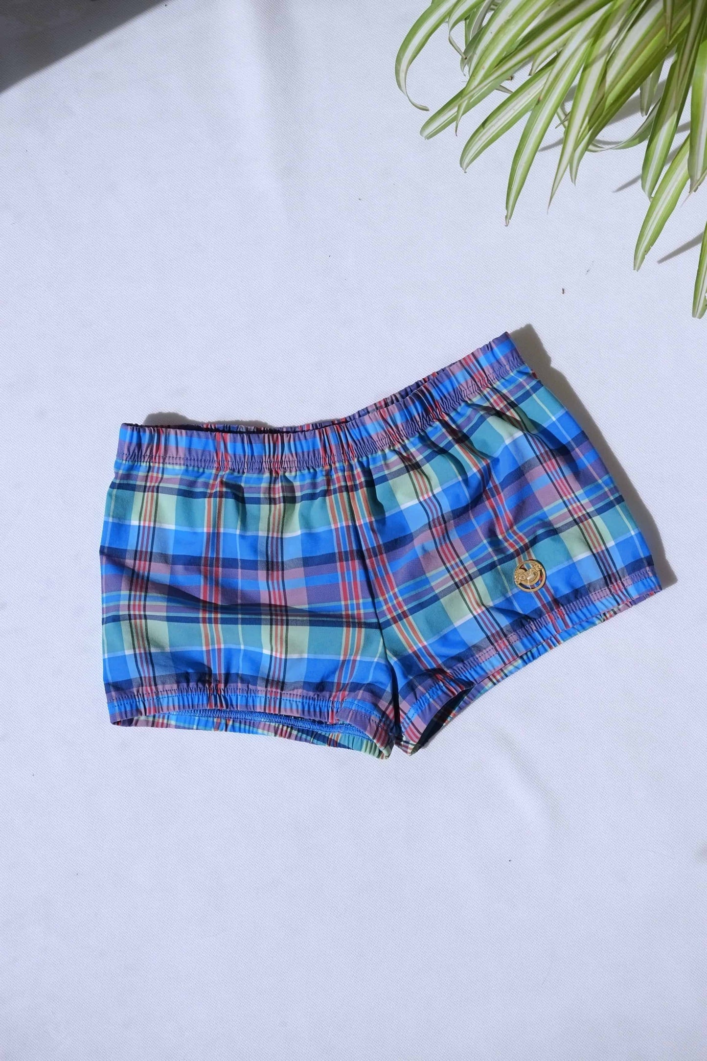 A single pair of SOLAR brand vintage 70s men's blue and green plaid square-cut swim briefs with a gold metal logo.