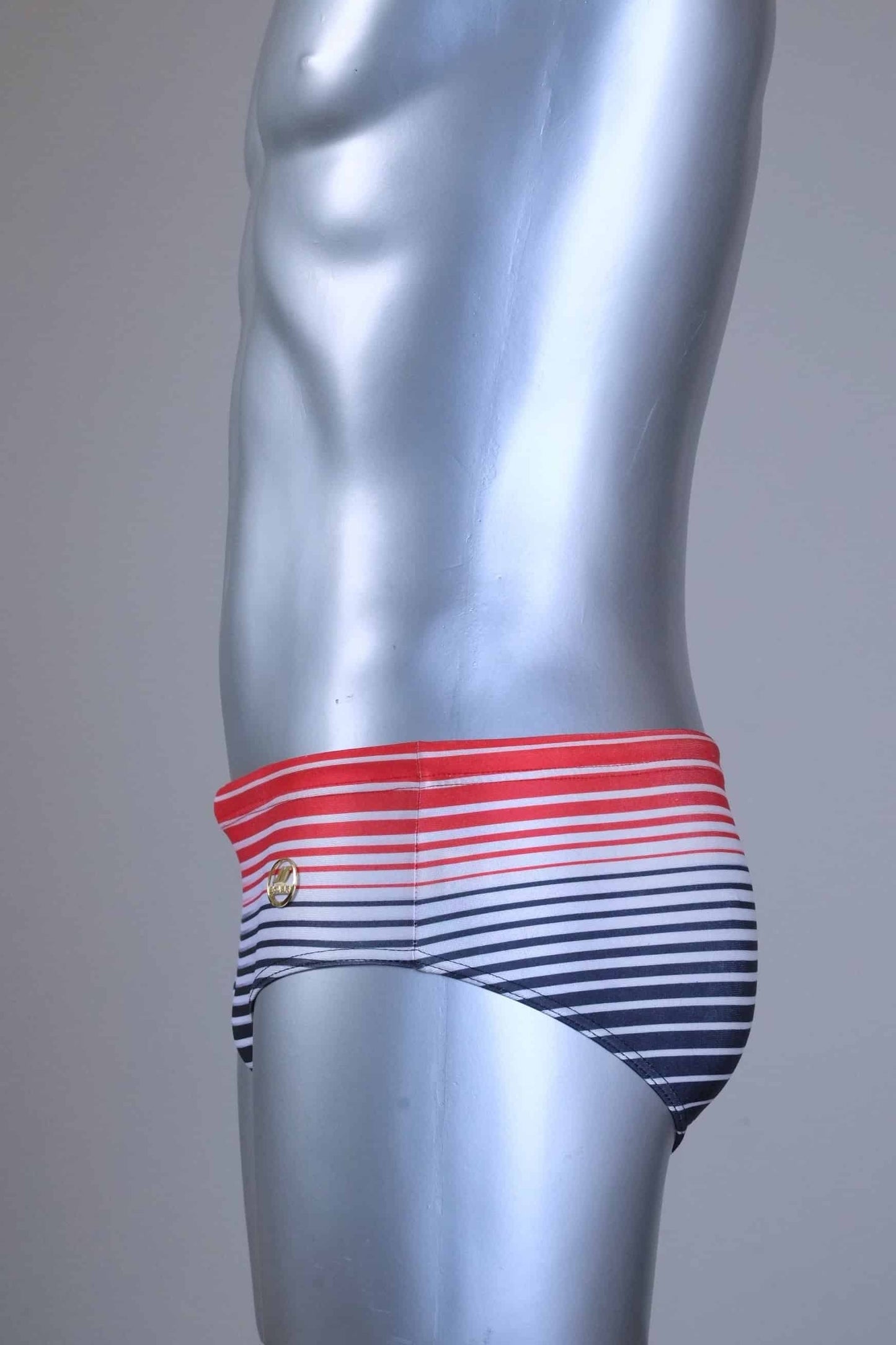 Side view of a Vintage 80s men's swim briefs featuring a red-to-black gradient horizontal stripe pattern on a silver mannequin