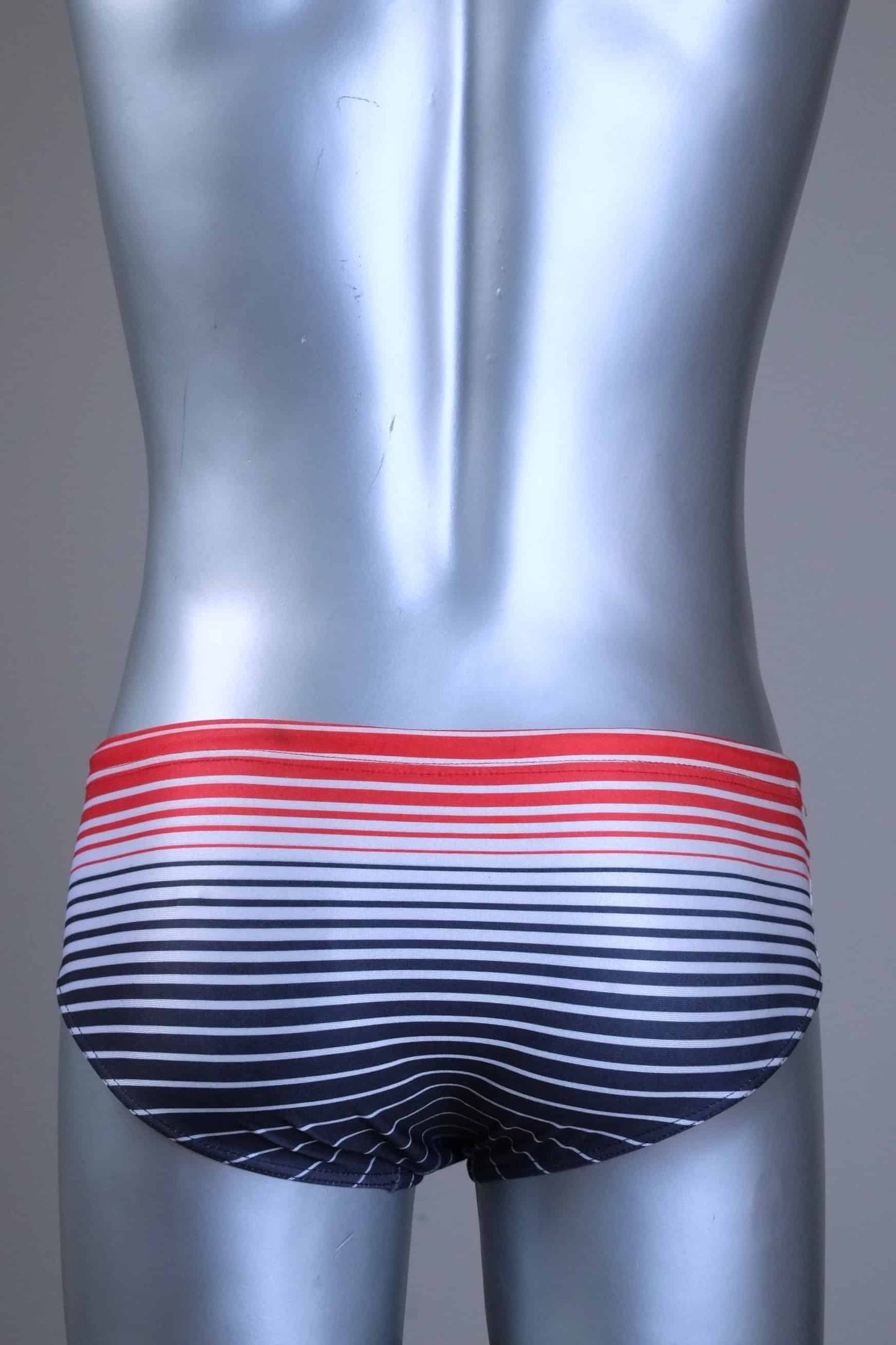 Back view of a Vintage 80s men's swim briefs featuring a red-to-black gradient horizontal stripe pattern on a silver mannequin