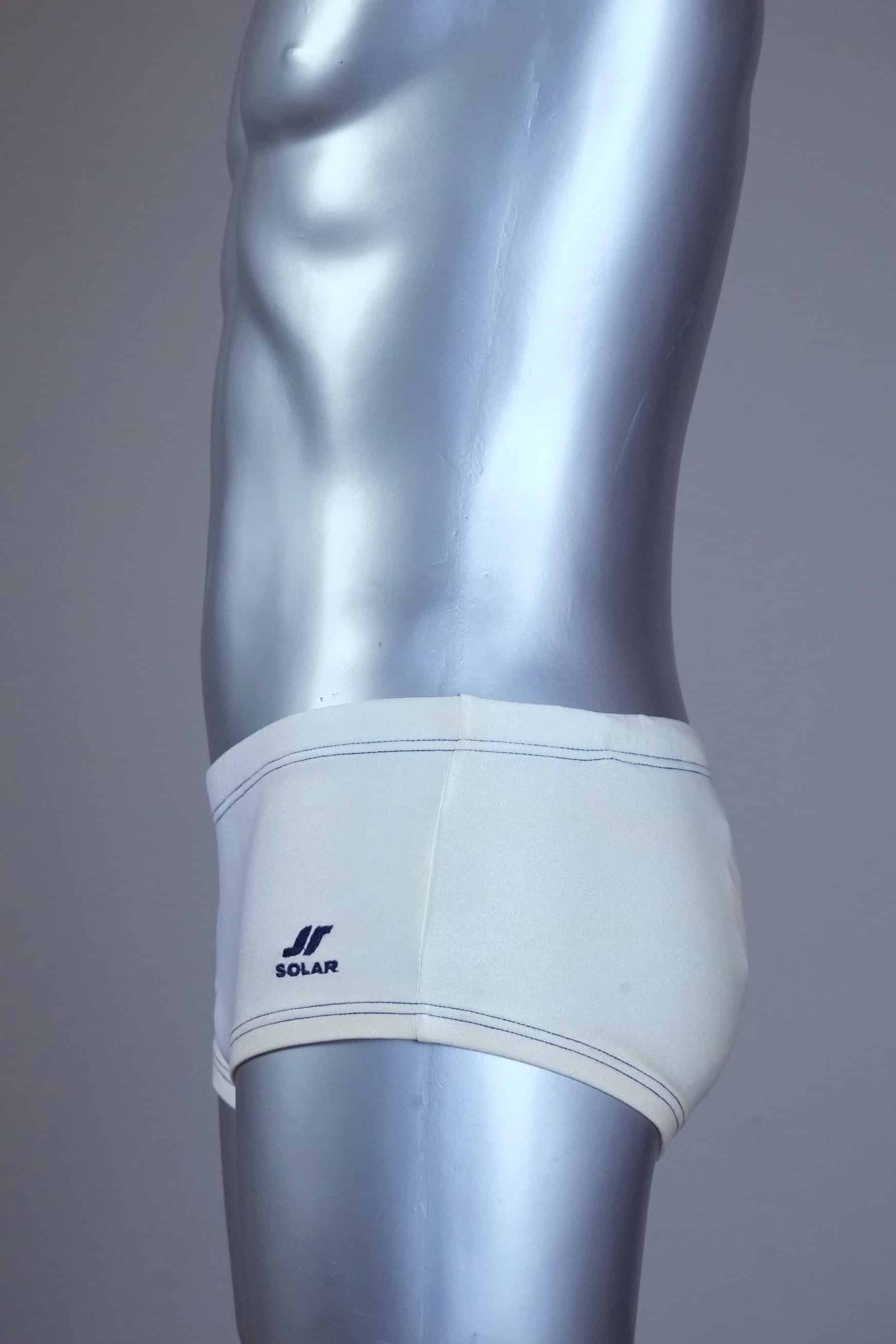Side view of Vintage white and blue swim briefs on a silver mannequin against a gray background