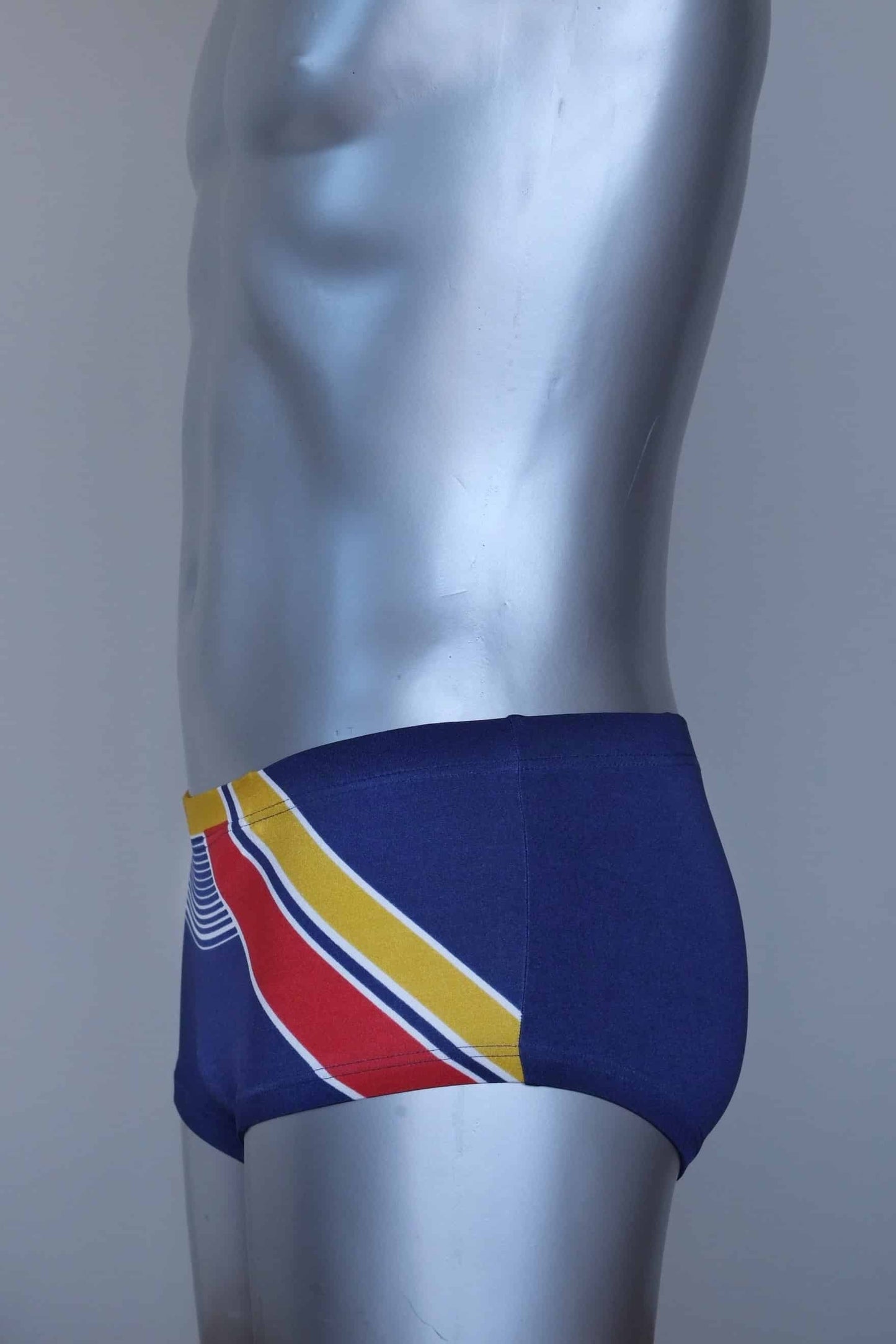 Side view of a Vintage navy and yellow striped men's swim briefs on a silver mannequin against a gray background