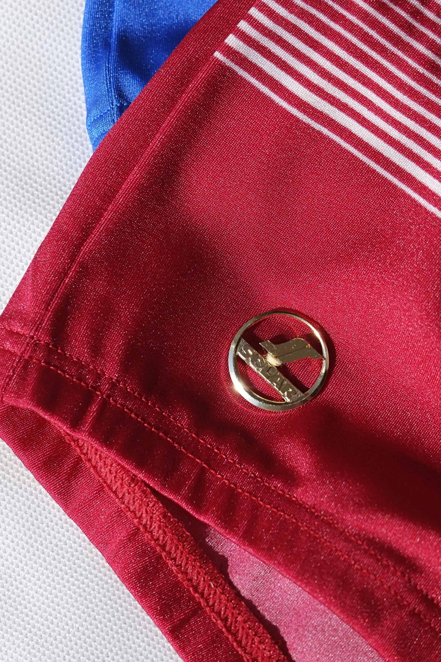 Close-up of a red fabric with a gold button on a white background