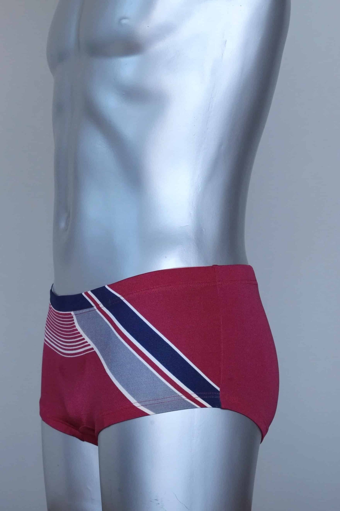 Side view of a Vintage burgundy and navy striped men's swim briefs on a silver mannequin against a gray background