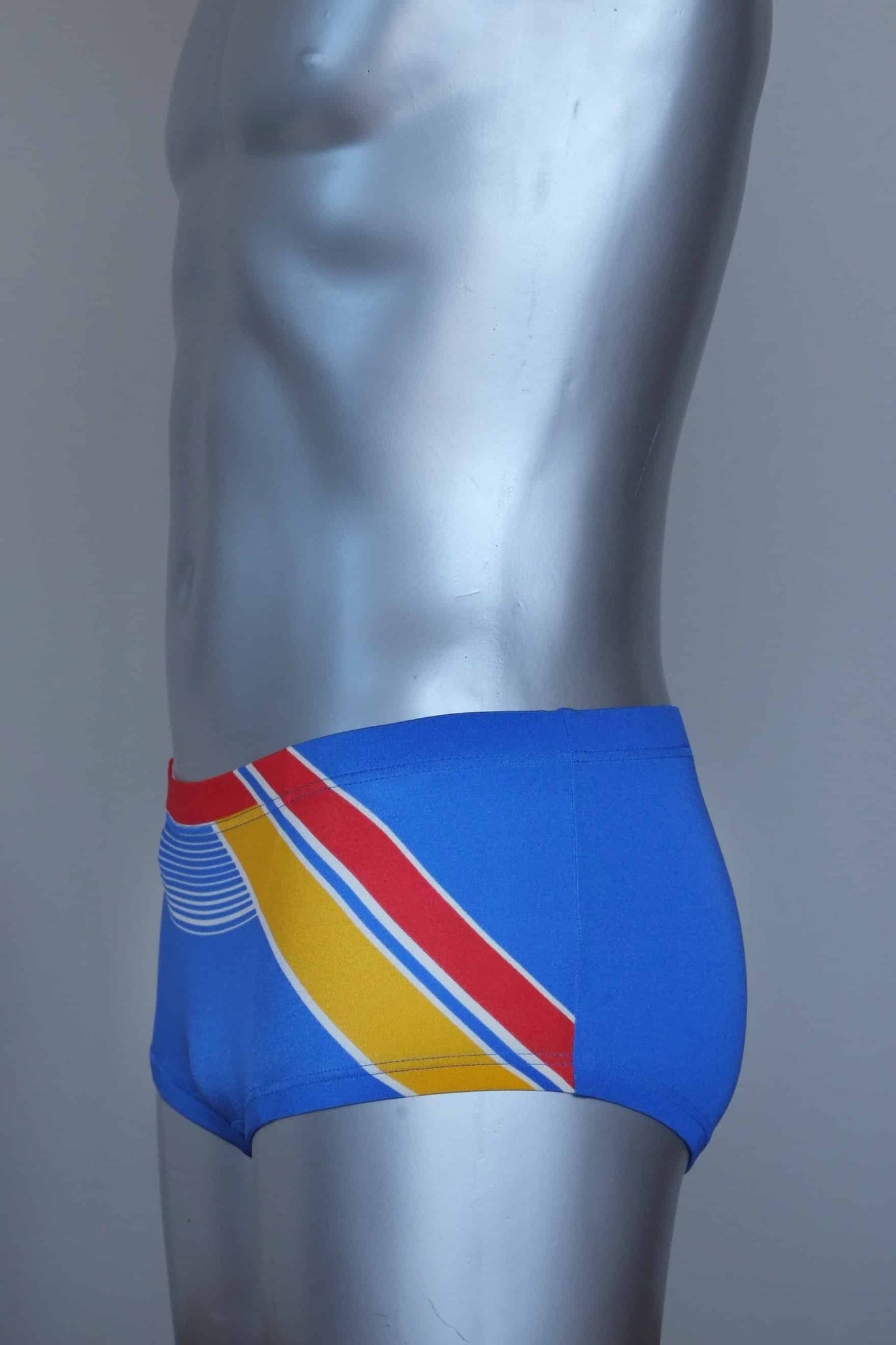 Side view of a Vintage blue and yellow striped men's swim briefs on a silver mannequin against a gray background