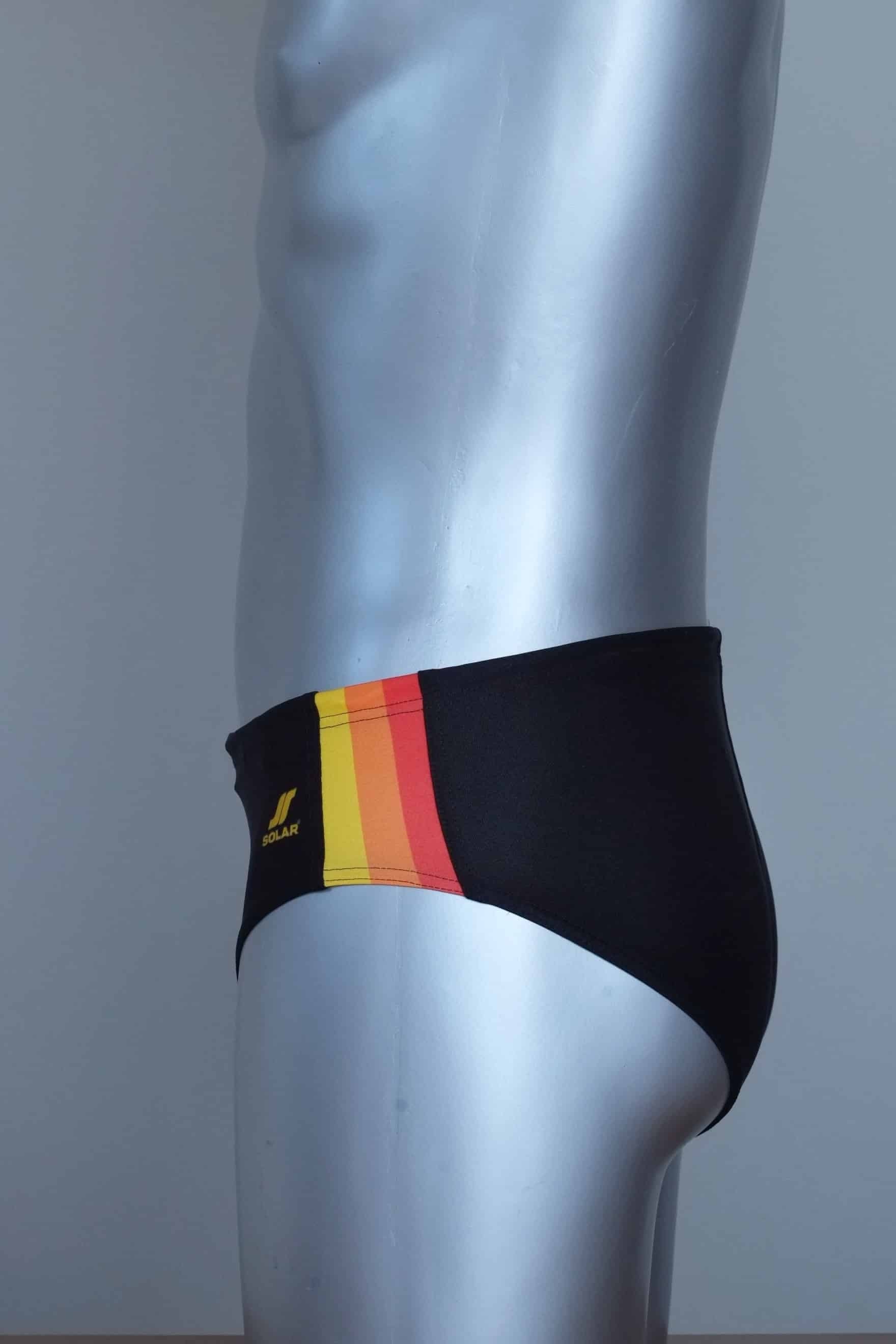 Side view of vintage black swim briefs with colorful side band on a mannequin against a gray background