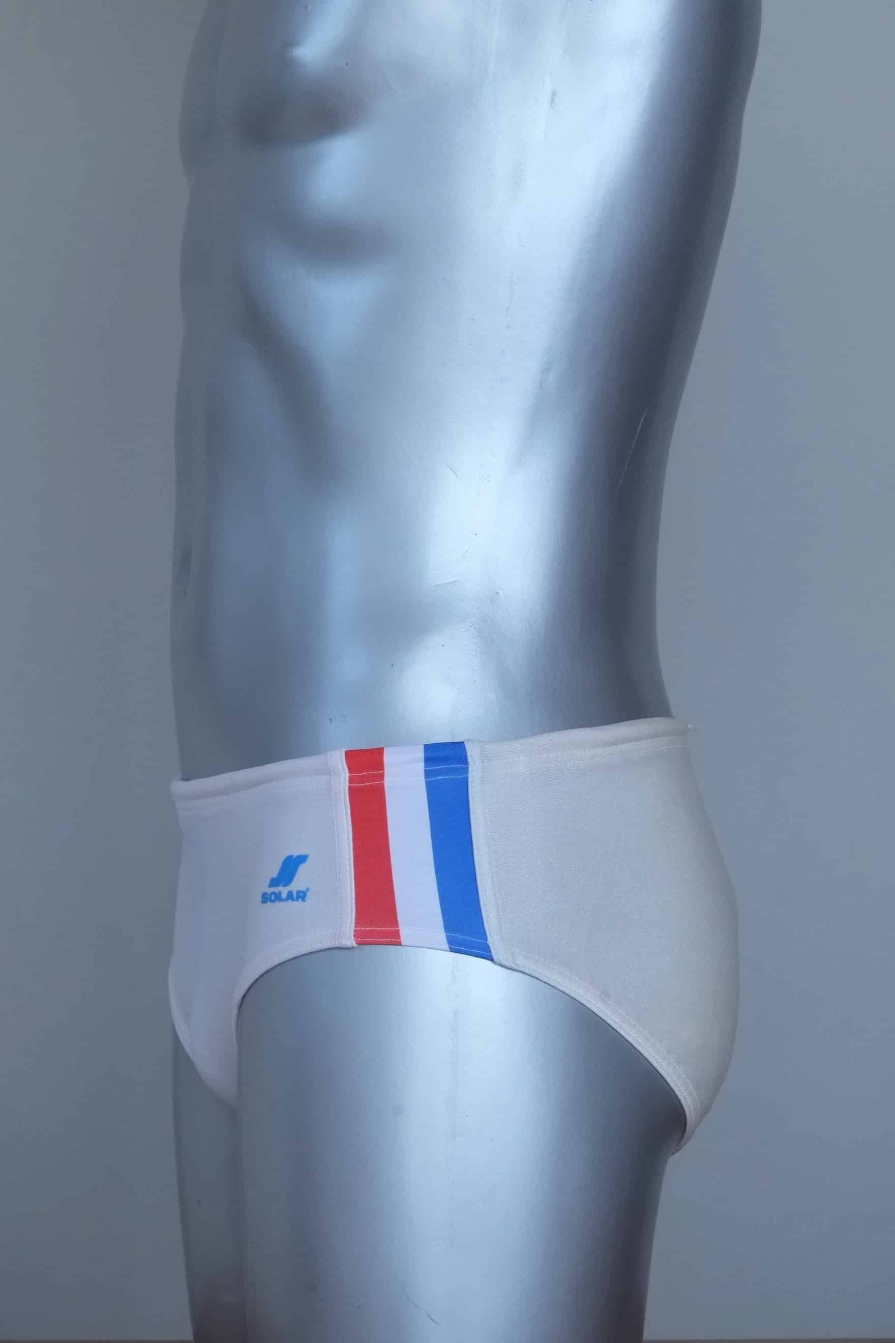 Side view of vintage white swim briefs with colorful side band on a mannequin against a gray background