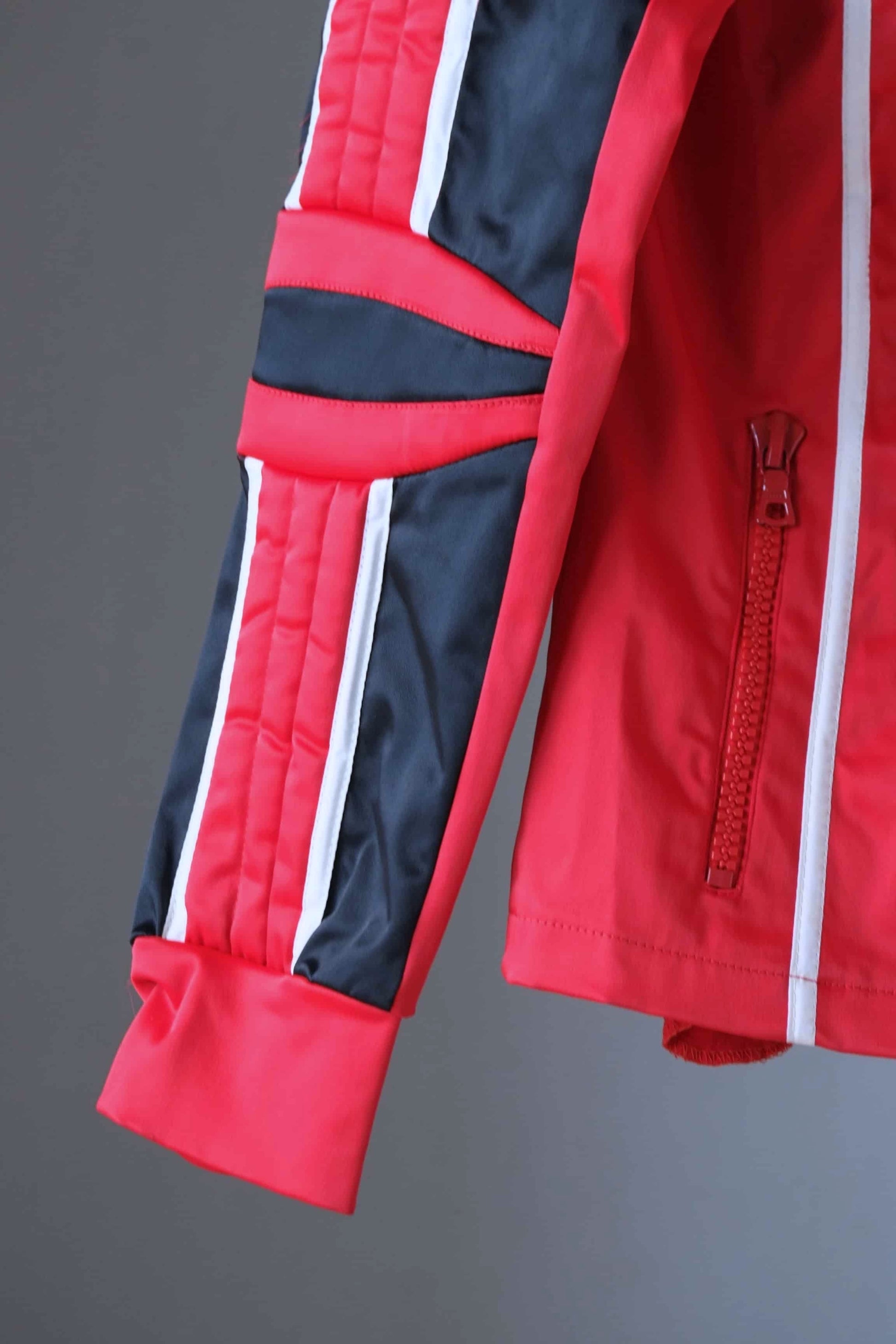 Detail of the sleeve of a vintage Sportalm ski jacket, showing the red, black, and white color-blocking, padded elbow, and white piping.