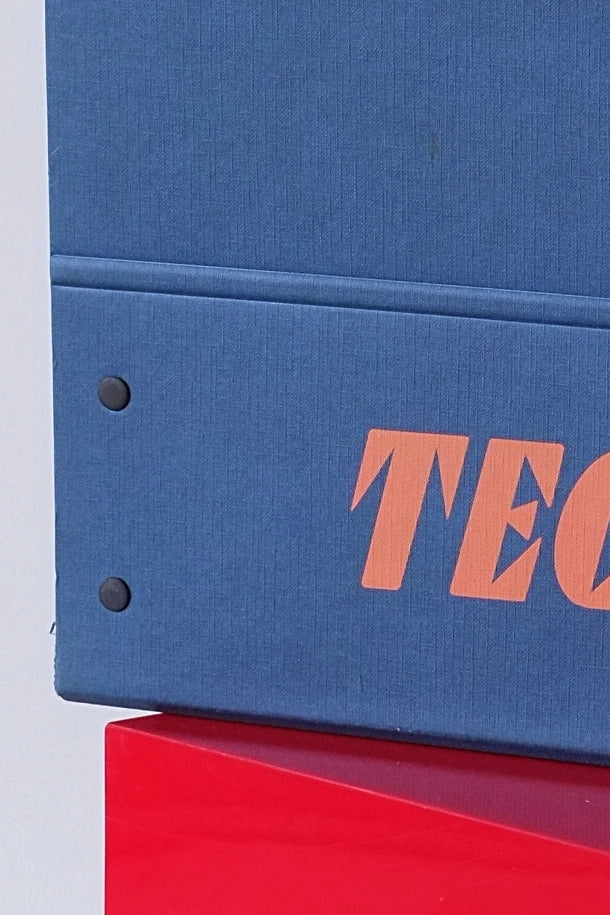 Close-up of the case material and printed orange Tecnica logo on textured blue cardboard.