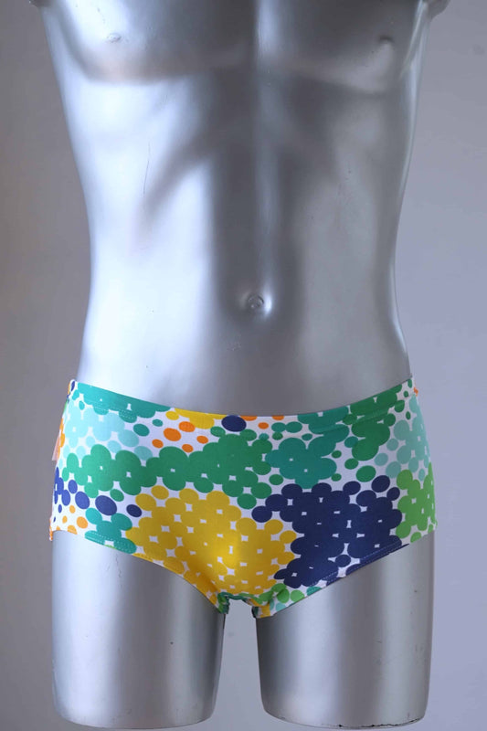 TROPIC Vintage Retro Dot Print Swim Briefs on a silver mannequin, showcasing the blue-green variant with a vibrant geometric dotted design. The pattern includes shades of green, blue, yellow, and orange dots for a bold, retro look.