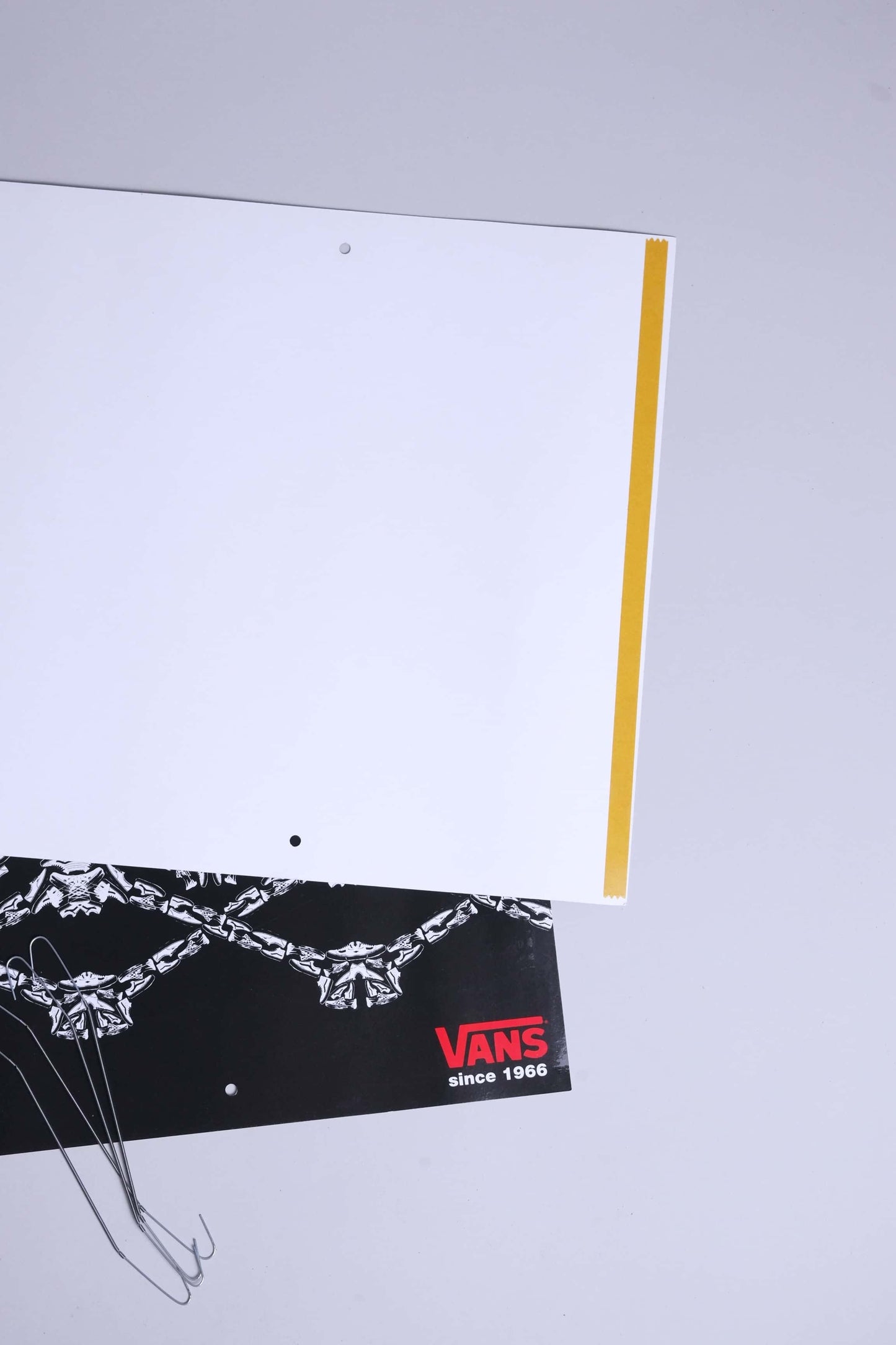 Close-up of backside with yellow adhesive strip and punched holes for wire hooks