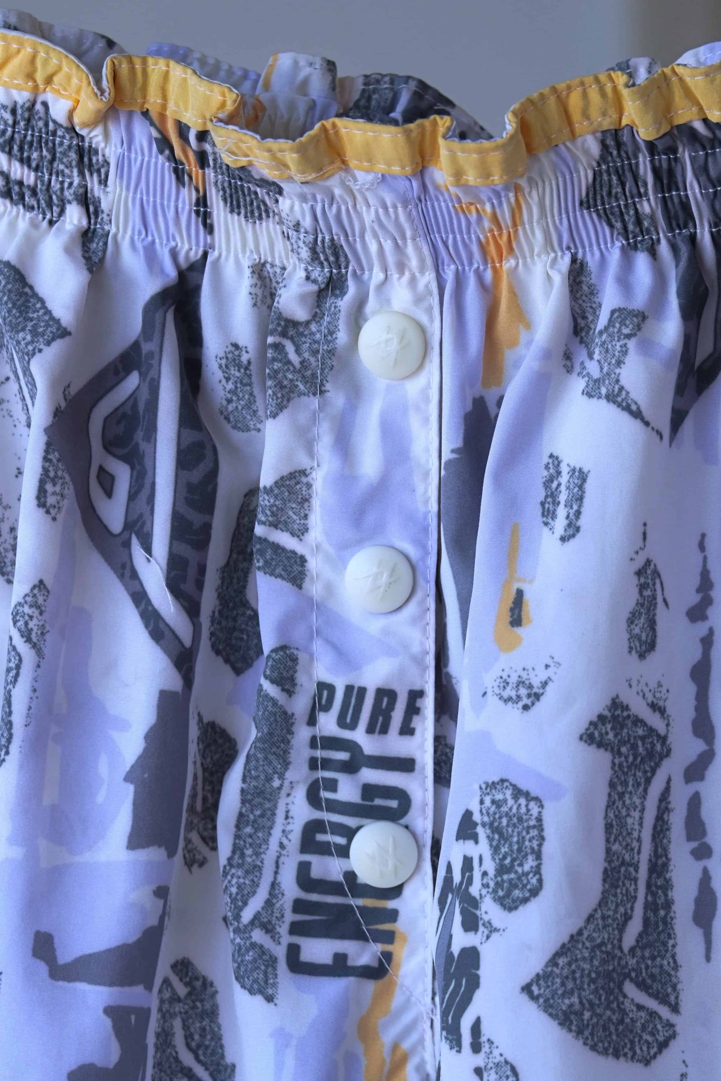 Close view of the front buttons of vintage printed volkl tennis shorts on hanger