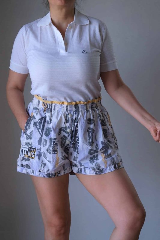 Model wearing a white polo and vintage printed volkl tennis shorts