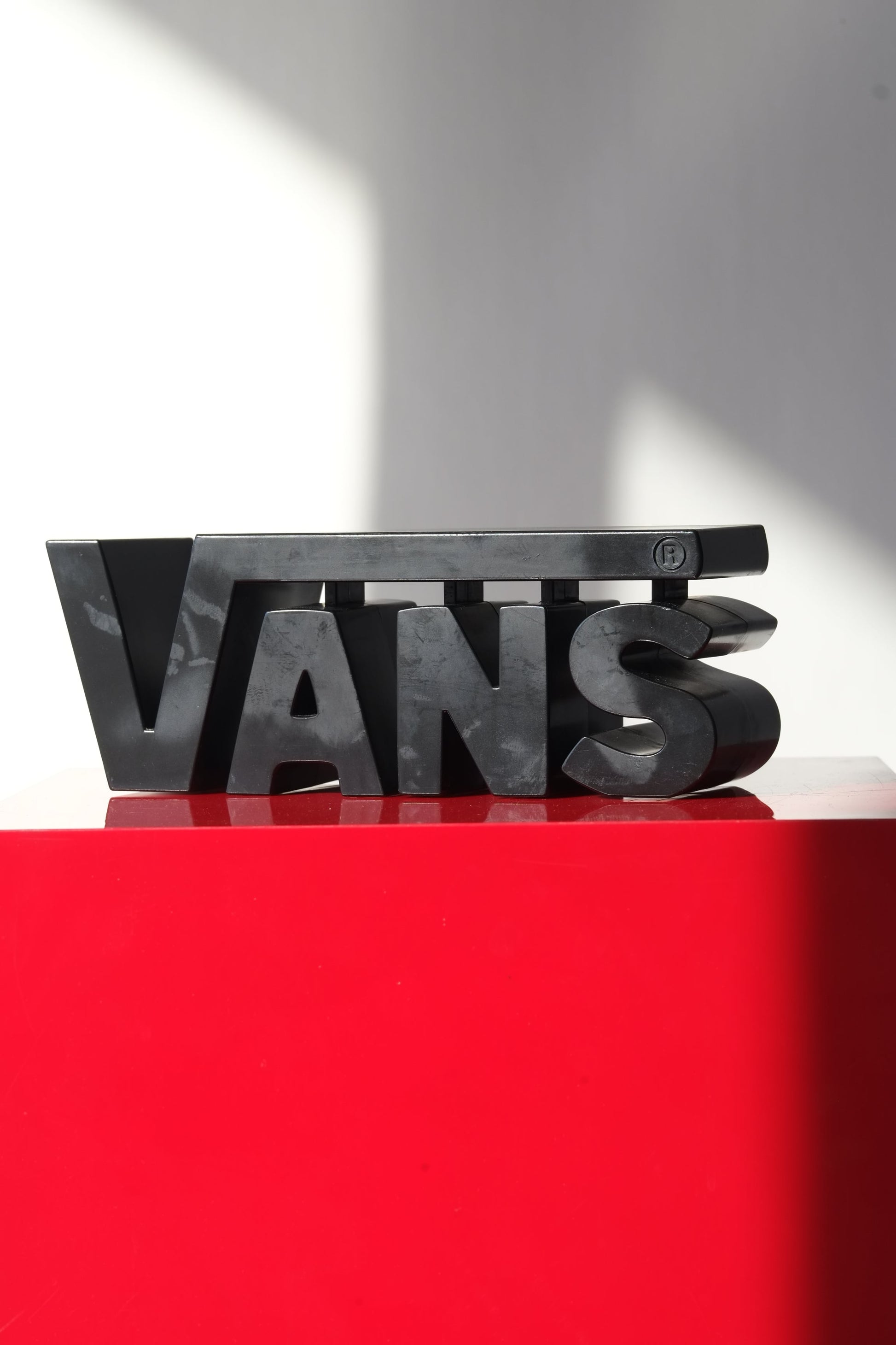 Angled close-up of the Vans 3D Y2K display logo showing surface wear and reflective black plastic texture.