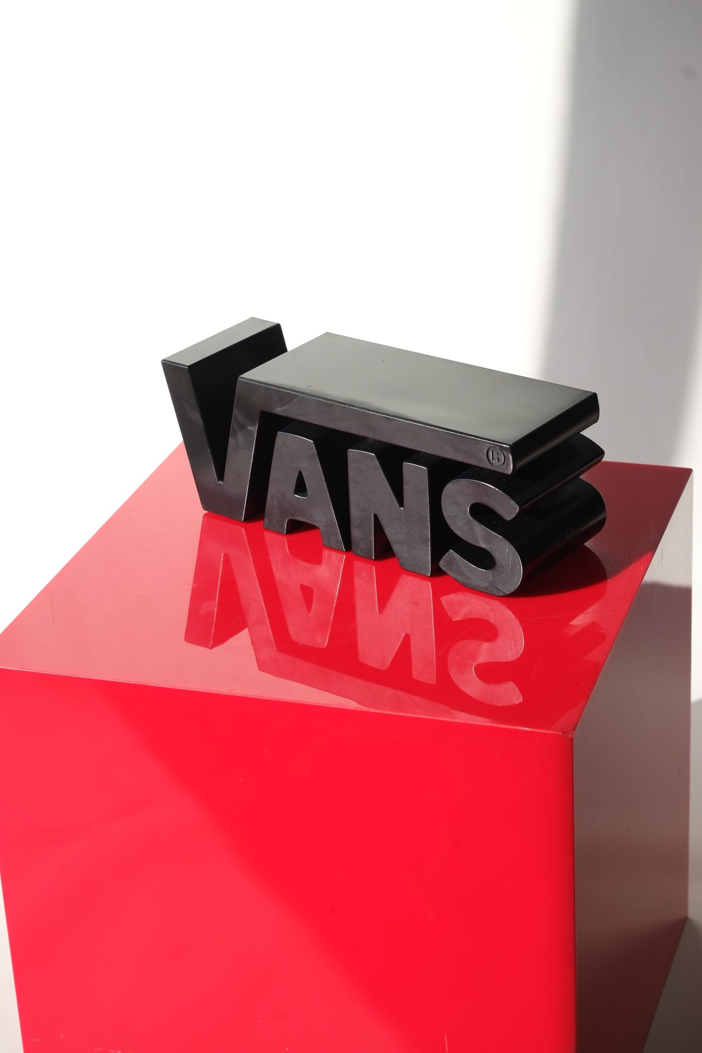 Front view of the Vans Y2K dealer display sign with bold 3D lettering resting on red pedestal in bright lighting.