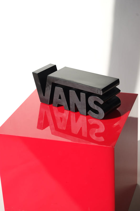 Front view of the Vans Y2K dealer display sign with bold 3D lettering resting on red pedestal in bright lighting.
