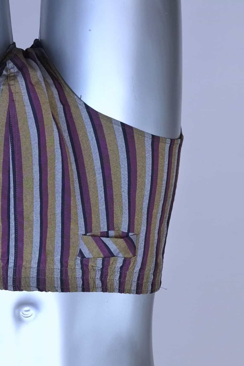 Close view of a vintage late 1950s to early 1960s men's swim brief on a silver mannequin. The brief features vertical stripes in muted brown, grey, and maroon tones, with a small front flap pocket.