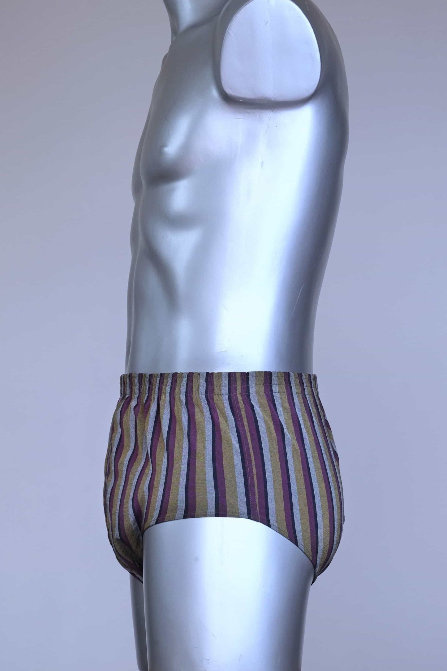 Side view of a vintage late 1950s to early 1960s men's swim brief on a silver mannequin. The brief features vertical stripes in muted brown, grey, and maroon tones, with a small front flap pocket.