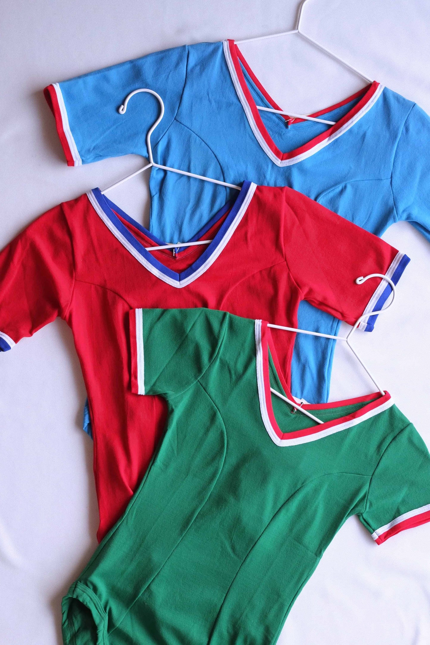Zofina vintage 70s short sleeve leotards in red, green, and blue on white hangers.