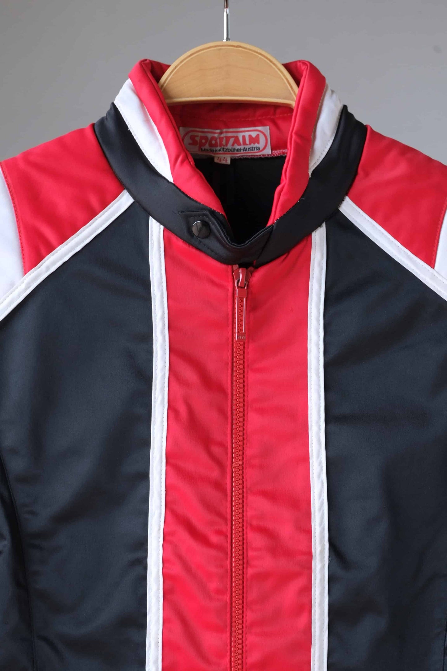 Close-up of the collar and label of a vintage Sportalm ski jacket. The jacket features a red and white striped collar and the Sportalm logo.