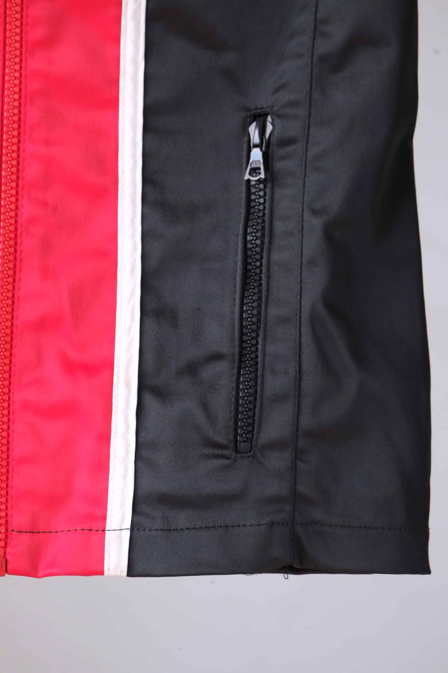 Close-up of the zippered pocket on a vintage Sportalm ski jacket, showing the red and black color-blocking.