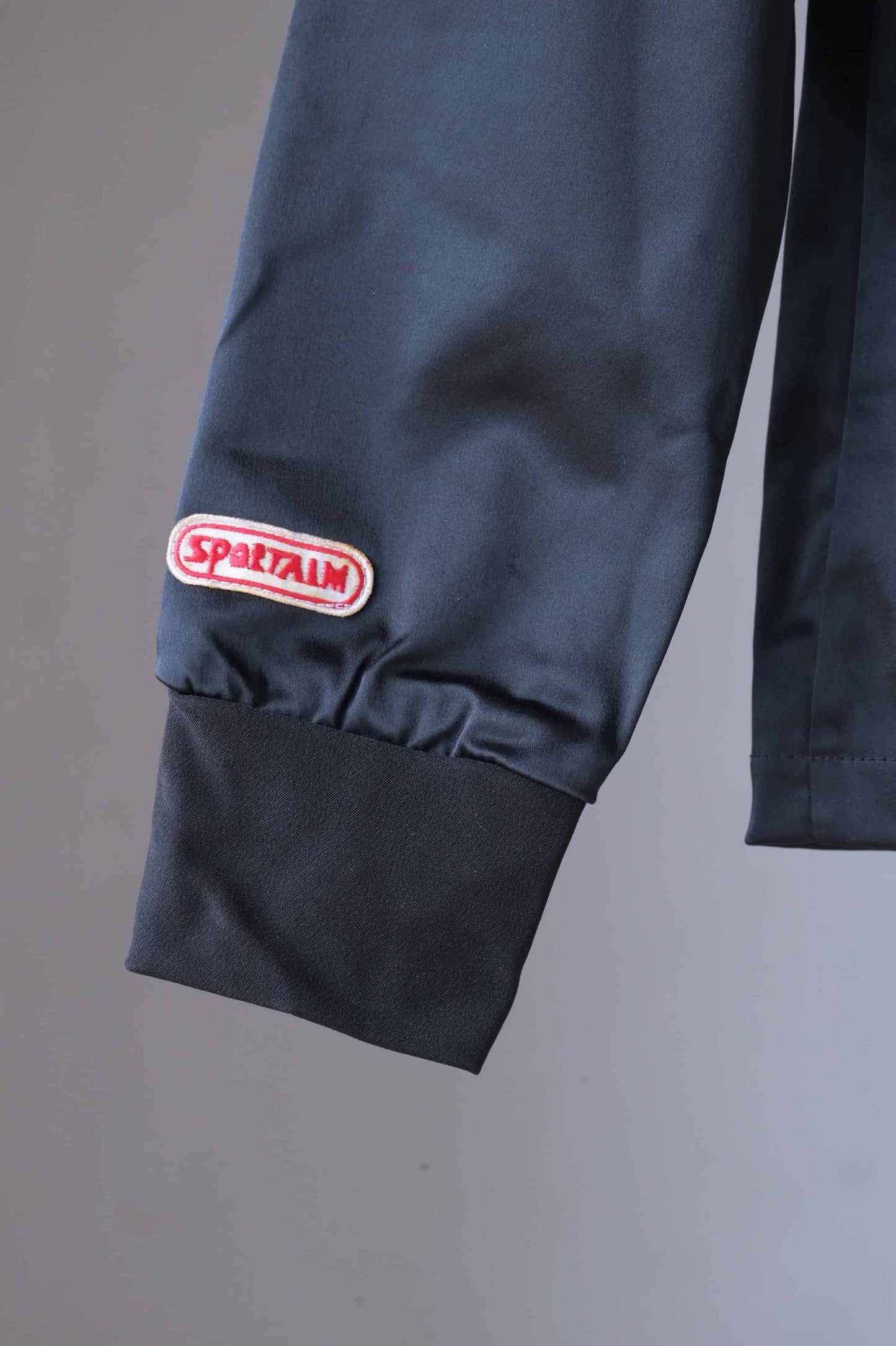 Close-up of the Sportalm logo patch on the sleeve of a vintage ski jacket. The jacket also features a ribbed cuff.