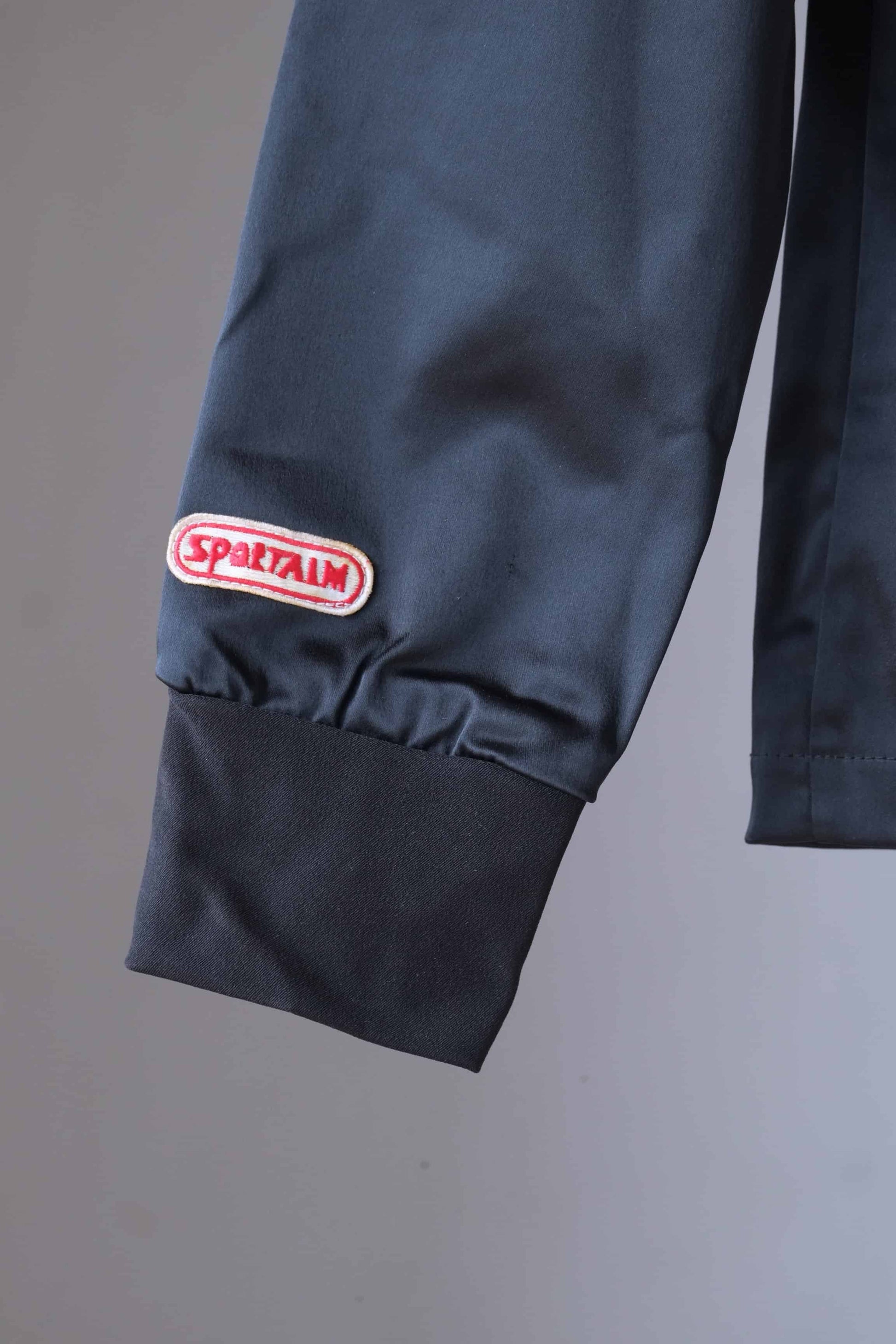 Close-up of the Sportalm logo patch on the sleeve of a vintage ski jacket. The jacket also features a ribbed cuff.